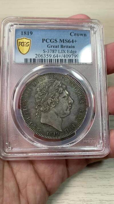 万国钱币拍卖第058期（万国新年大拍） PCGS MS64+ 1819年LIX英国乔治三世马剑克朗大银 英国马剑系列的开山之作 马剑图案由著名的意大利雕刻家Pistrucci设计 在钱币两面皆留下签名 这在当时是难以被接受的（通常只留首字母缩写） 此举也为后来首席雕刻师W.Wyon上位埋下伏笔 此枚无论底板，包浆，还是高点都堪称无可挑剔  一枚乔三马剑的标准器  高分价格越来越看不懂的存在 此次贴脸入手机会切勿错过