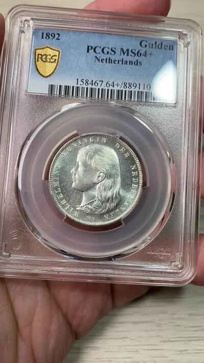万国钱币拍卖第058期（万国新年大拍） PCGS MS64+ 1892年荷兰威廉明娜女王少女头像一盾银币 人见人爱的小萝莉。车轮霜光，打制极佳。底板类镜面质感，优异状态无愧一个加号，BU级别越来越难碰到了。瑞士拍卖NGSA刚拍的一枚66分到手约合RMB九万元。大热门品种，潜力十足，自藏级佳品。
