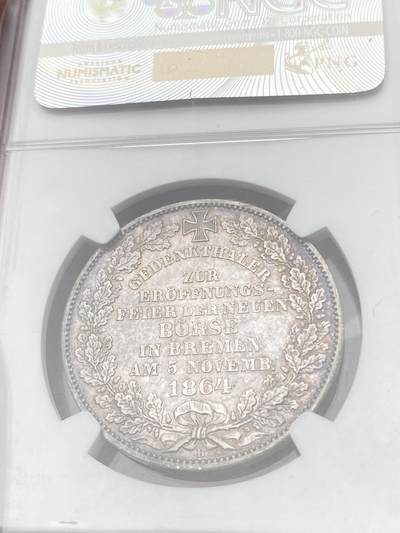 万国钱币拍卖第058期（万国新年大拍） NGC MS64 1864年不莱梅证券交易所泰勒 不莱梅自由市名誉品种 汉诺威造币厂精工之作 为庆祝不莱梅交易所的成立而发行 发行量仅5000枚 高分越来越难的品种 优雅淡彩状态舒适 不莱梅市徽上方刊德文“上帝保佑贸易与航运”这座美丽的新哥特风格建筑在1943年毁于战火 庆幸的是还能在此币上欣赏她的美丽