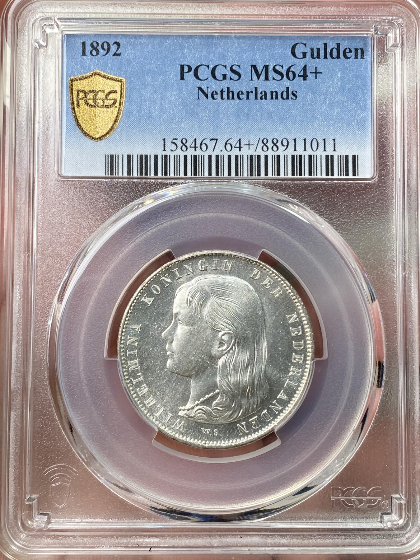 万国钱币拍卖第058期（万国新年大拍） PCGS MS64+ 1892年荷兰威廉明娜女王少女头像一盾银币 人见人爱的小萝莉。车轮霜光，打制极佳。底板类镜面质感，优异状态无愧一个加号，BU级别越来越难碰到了。瑞士拍卖NGSA刚拍的一枚66分到手约合RMB九万元。大热门品种，潜力十足，自藏级佳品。