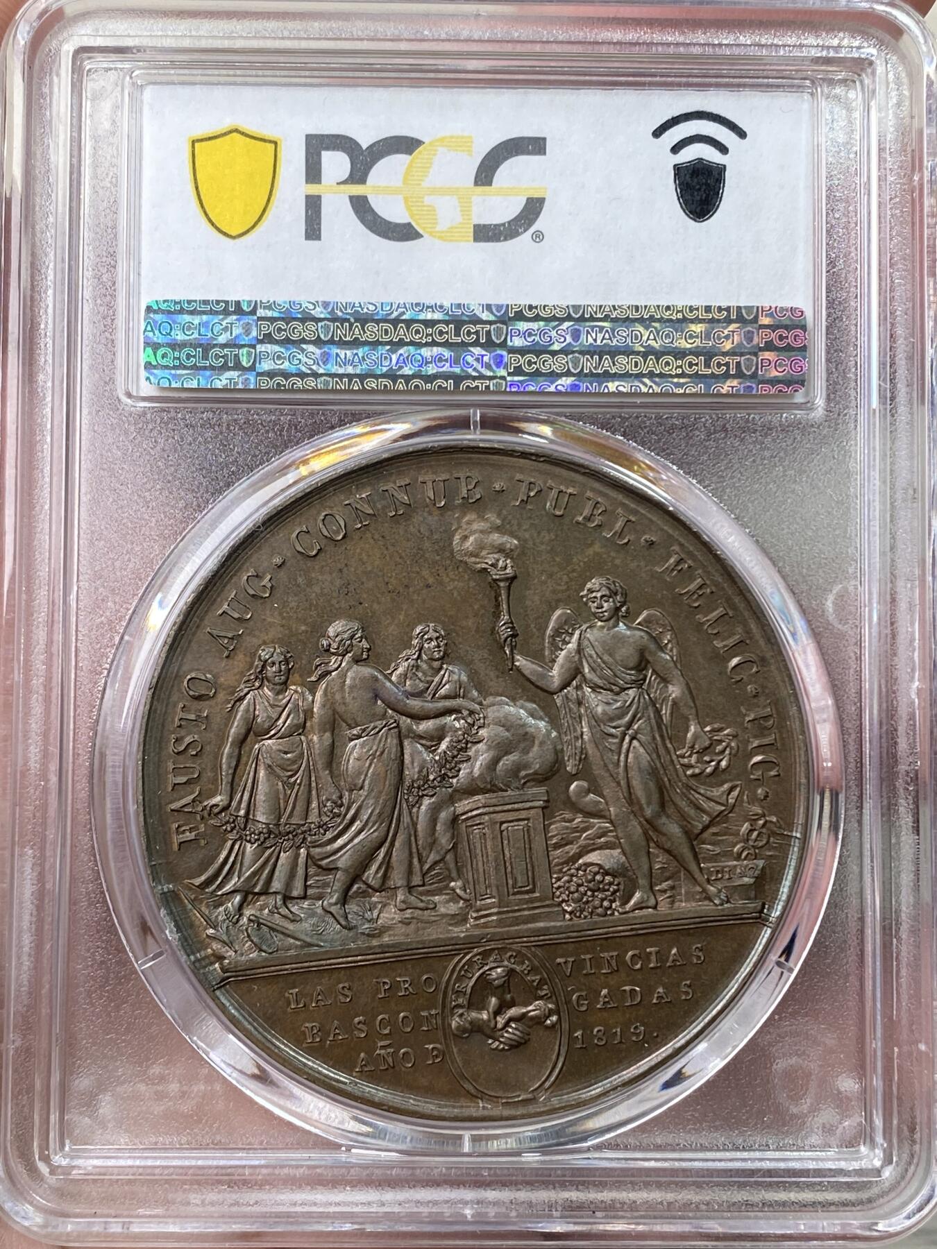 万国钱币拍卖第058期（万国新年大拍） PCGS SP64 1819年西班牙国王皇家婚礼原铸铜章 PC数据库唯一冠军。费迪南德七世，紫铜色包浆，高浮雕底板完美，44mm大尺寸厚实巧克力。正面是费迪南德和玛丽亚半身像，反面是圣坛前的手持祝福花环的美惠三女神，天使丘比特手持火炬。王室夫妇双手与上帝之手紧紧相握。两面均采用精心的艺术设计，具有动感和表现力的细节。明亮的铜色表面充分反射光线，实物很漂亮。