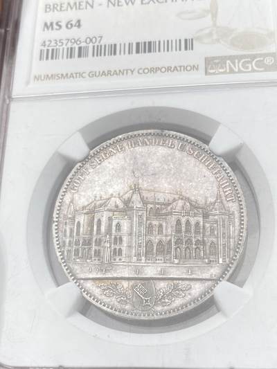 万国钱币拍卖第058期（万国新年大拍） NGC MS64 1864年不莱梅证券交易所泰勒 不莱梅自由市名誉品种 汉诺威造币厂精工之作 为庆祝不莱梅交易所的成立而发行 发行量仅5000枚 高分越来越难的品种 优雅淡彩状态舒适 不莱梅市徽上方刊德文“上帝保佑贸易与航运”这座美丽的新哥特风格建筑在1943年毁于战火 庆幸的是还能在此币上欣赏她的美丽