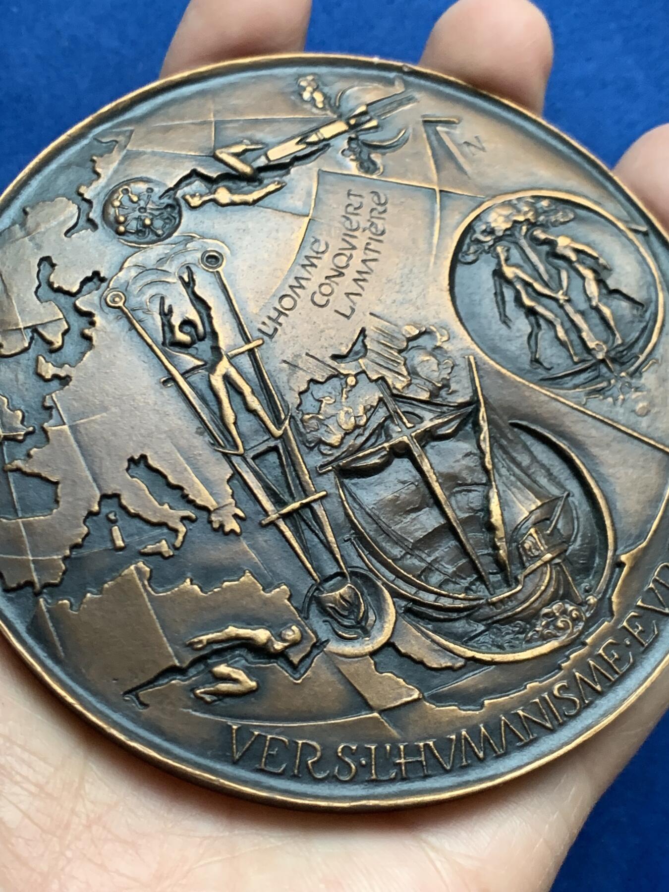 《竞宝斋》第452场 周日，周一 2场连拍 （全场包邮，欢迎送拍） 名家名作 德梅特尔·阿纳斯塔斯设计 迈向欧洲人文主义 超大号纪念铜章 506.5克，96.5mm，丰饶角铜标，此为原铸章， 市场出现大部分为边铭处带年份的后铸章  正面： 在地球仪上，描绘了宙斯化身为公牛掳走欧罗巴仙女的传说场景；下方圆形图案中为十字架上的基督及其花押字   背面：在欧洲地图上，三位分别代表地下、陆地与太空领域的主宰者。圆形图案中，两人在象征欧洲的树下握手，下方是希望之舟。