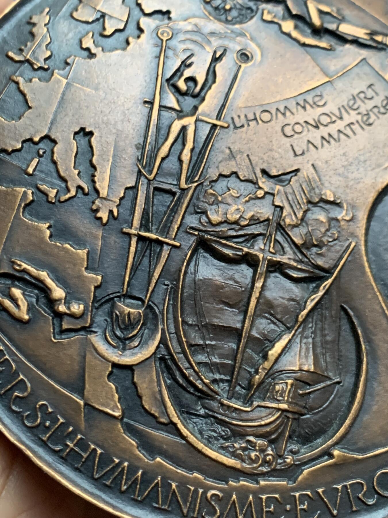 《竞宝斋》第452场 周日，周一 2场连拍 （全场包邮，欢迎送拍） 名家名作 德梅特尔·阿纳斯塔斯设计 迈向欧洲人文主义 超大号纪念铜章 506.5克，96.5mm，丰饶角铜标，此为原铸章， 市场出现大部分为边铭处带年份的后铸章  正面： 在地球仪上，描绘了宙斯化身为公牛掳走欧罗巴仙女的传说场景；下方圆形图案中为十字架上的基督及其花押字   背面：在欧洲地图上，三位分别代表地下、陆地与太空领域的主宰者。圆形图案中，两人在象征欧洲的树下握手，下方是希望之舟。