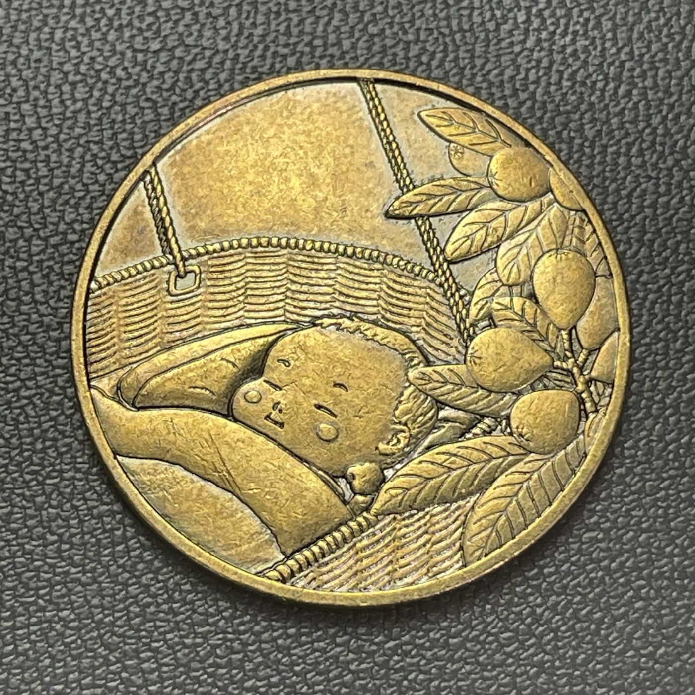 回流1228 2014年甲午马年铜质纪念章 襁褓中安睡的婴儿，旁侧搭配橘子树（橘与“吉”谐音，寓意吉祥），整体画面传递出新生、平安的美好祝愿，结合2014甲午年的时间背景，也暗含对马年新生儿的祝福。