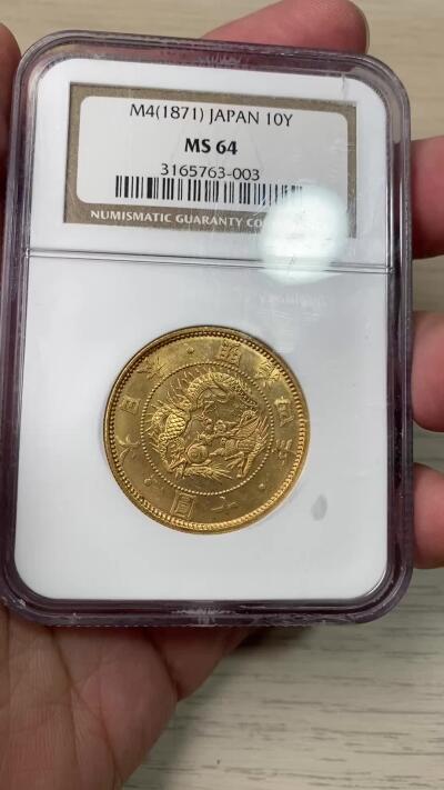 万国钱币拍卖第058期（万国新年大拍） NGC MS64 1871年日本明治四年双旗旧十円大金币 日系经典名誉品种 大阪造币厂铸 背面中央是日本传统神话中三神器之一的八尺镜 上方是象征日本皇室的十六瓣八重表菊纹 两边则是象征天照与月读大神的旗帜 也是明治四年发行货币中的最大面值 打制深峻丝绸金光轻微类镜面质感 NGC老白盒顶级收藏品质 16.66G 900金 