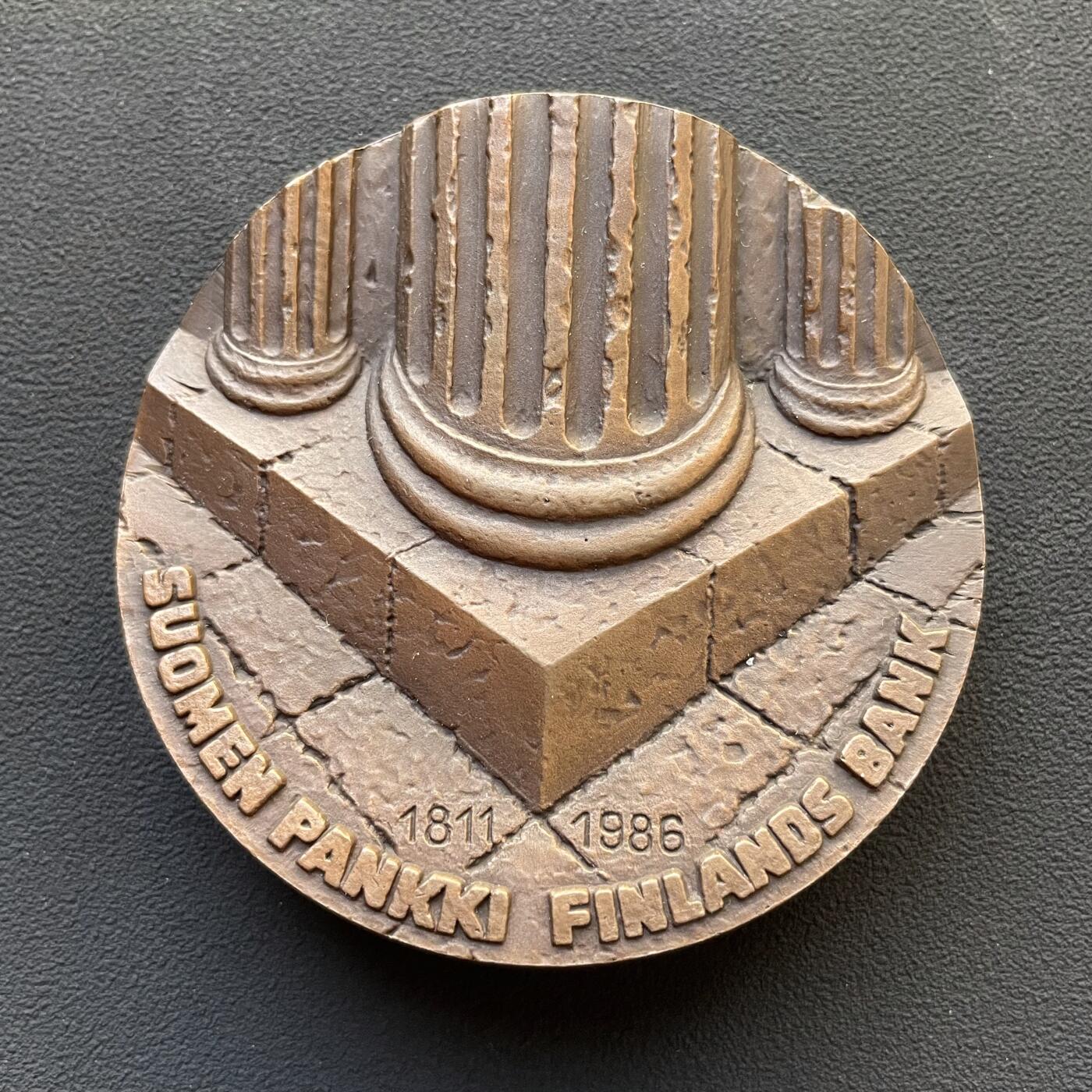 「木头集藏」章牌专场-第65场 芬兰银行（芬兰中央银行）175周年纪念加厚纪念大铜章，直径：70 mm，403g，特别加厚，超高浮雕，厚重压手。正面图案为高浮雕罗马柱基座，象征央行是芬兰国家的重要支柱基础。背面是抽象的芬兰地图高浮雕造型。 芬兰银行是芬兰共和国的中央银行，也是欧洲中央银行系统的成员。