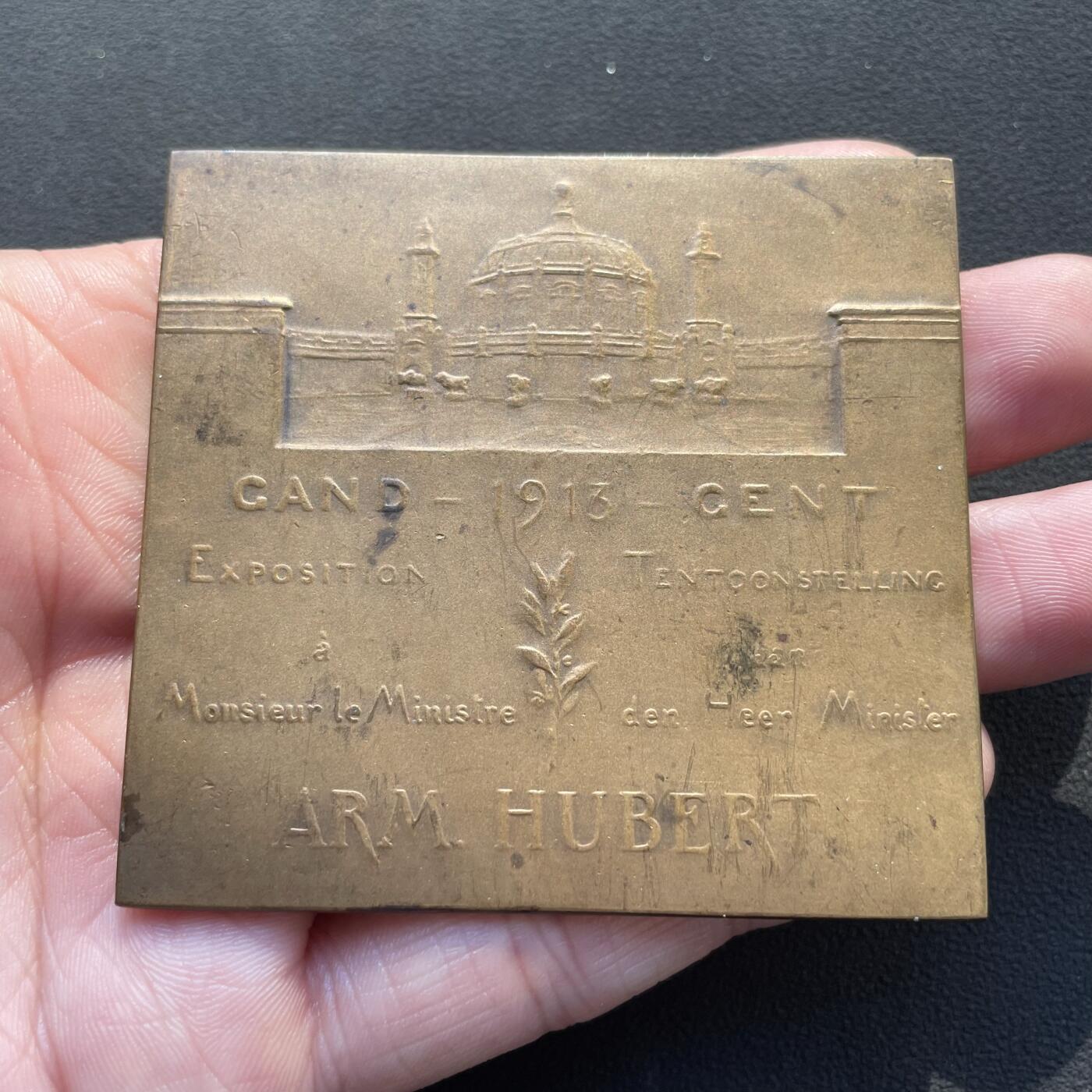 「木头集藏」章牌专场-第65场 G. Devreese ～1913年根特世博会—陆军部长于贝尔纪念大铜章，尺寸：65 × 61mm，102.5g，欧洲老资格的商业中心城市根特举办了世博会。此章在当时定制，作为陆军部长于贝尔馈赠参加世博会嘉宾的纪念品。正面为陆军部长于贝尔坐在书桌前的椅子上阅读报刊的形象，背面为根特世博会展馆，以及“1913年根特世博会”“陆军部长Arm. Hubert”等铭文。