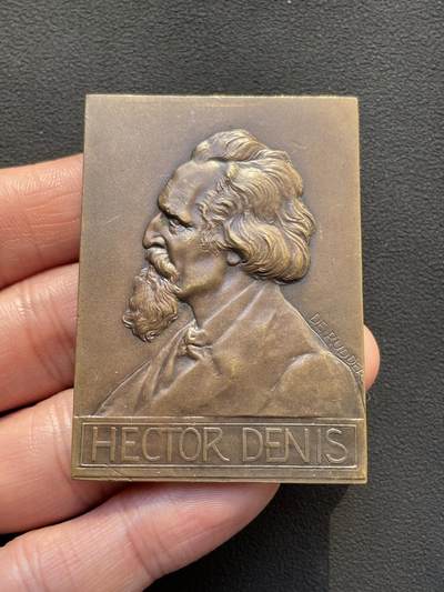 「木头集藏」章牌专场-第65场 - 比利时布鲁塞尔自由大学教授赫克托·丹尼斯纪念章， 尺寸：59×42mm，81.5g。 赫克托·丹尼斯教授于1878年至1912年间，在自由大学担任教职34年。这枚长方形铜章就是为纪念他的卓越奉献而定制的。 正面是教授的左侧胸像，下方铭文是他的姓名。背面为知识女神点向象征光明的太阳图案，上方三行铭文意为“自由大学”“教授”“1878年至1912年”。