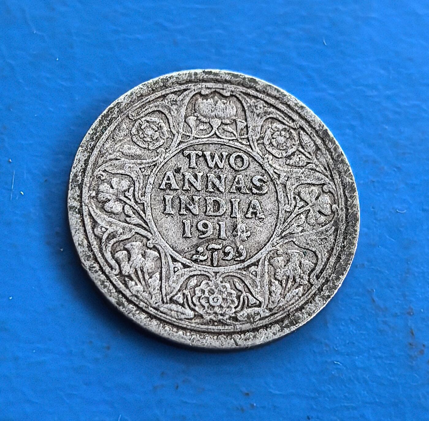 外国优质老铜币高银银币，周六九点倒数截拍，满百包邮，持续收拍 英属印度1914 年 2 安那银币，正面乔治五世 “国王 - 皇帝” 像，背面花卉纹环饰 “TWO ANNAS INDIA 1914” 及印度文。银质见证英殖民统治，设计融合英伦君主与印度装饰，铸于一战前夕，属殖民货币稀有标本。承载跨文化统治脉络，为研究英印关系、帝国货币史的独特藏品，藏殖民时代交融印记 。