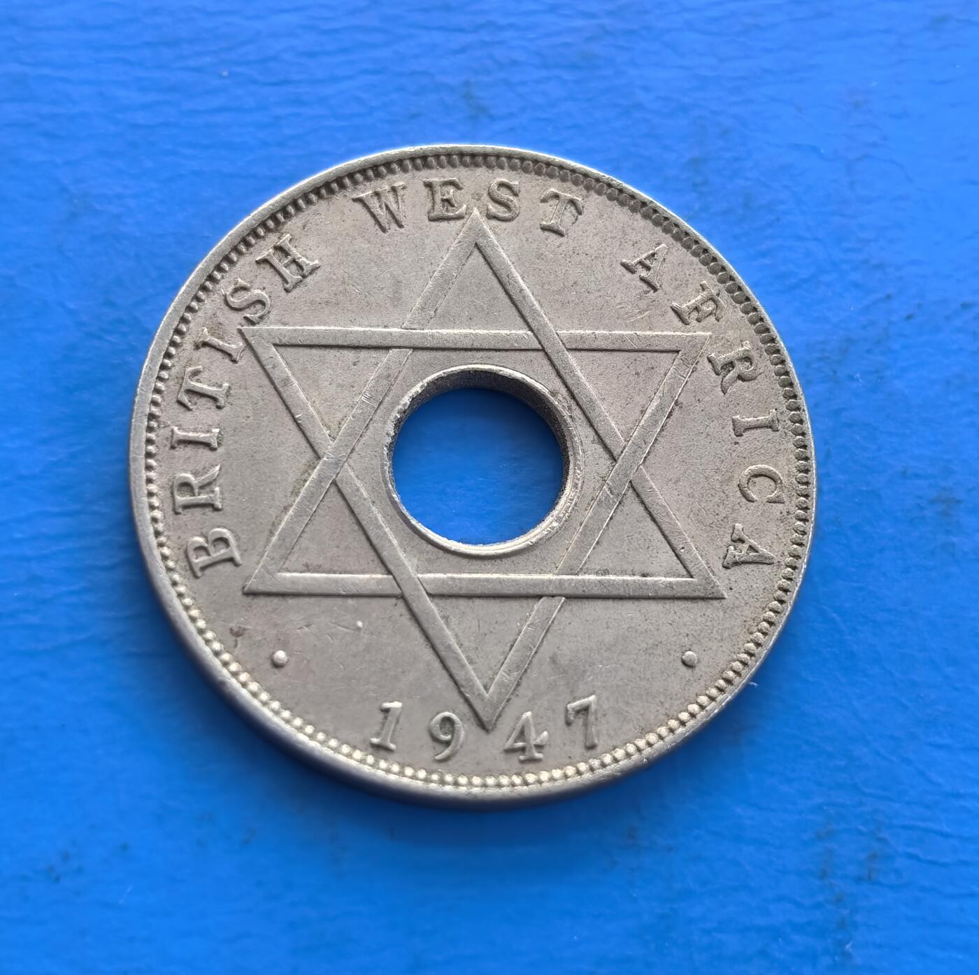 外国优质老铜币高银银币，周六九点倒数截拍，满百包邮，持续收拍 英属西非1947年半便士H版，中孔设计别致。正面集乔治六世王冠、王室铭文与阿拉伯文，背面六芒星分割纪年，融合殖民、宗教符号。诞生于二战后英殖民末期，见证帝国余晖，存世随岁月渐稀。作为多元文化碰撞的殖民币标本，解码西非历史，收藏兼具故事性与设计感 。