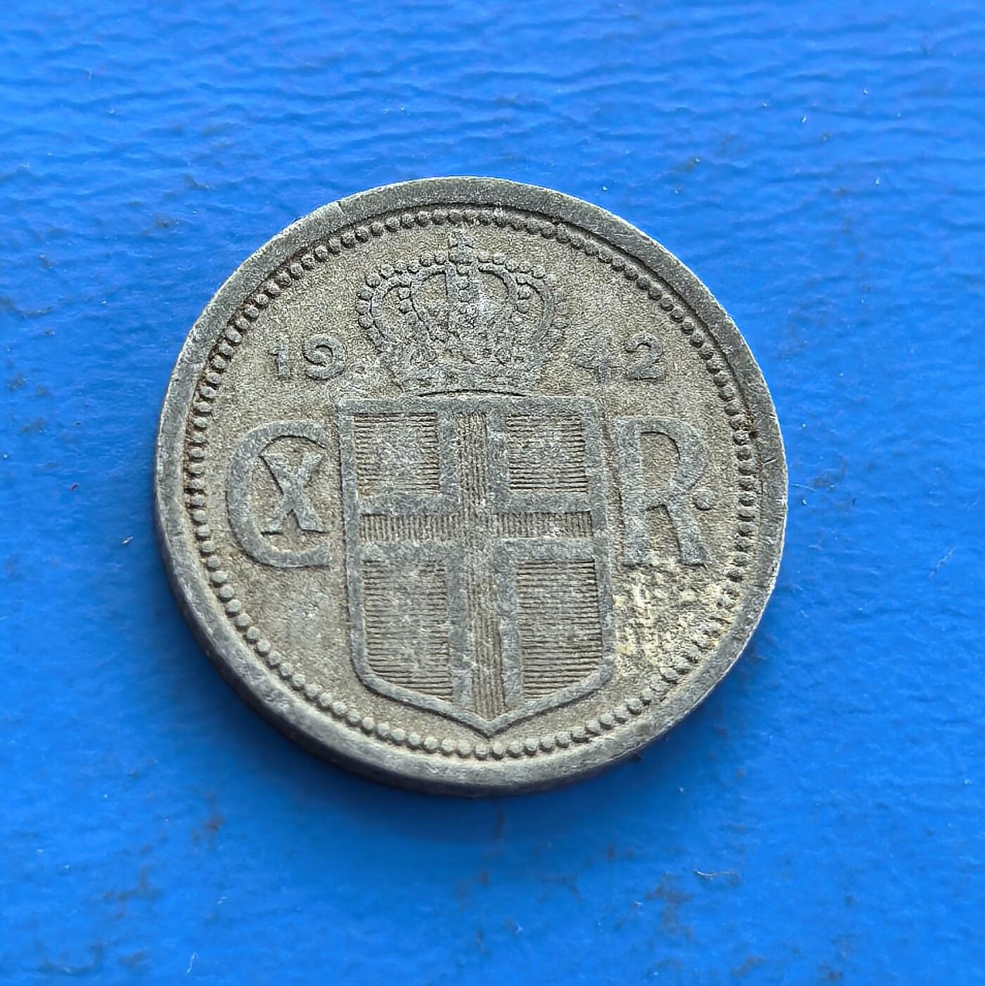 外国优质老铜币高银银币，周六九点倒数截拍，满百包邮，持续收拍 冰岛1942 年 25 奥拉，铸于二战丹麦被占、冰岛自治过渡期。正面冰岛语面值，背面丹麦王室纹章（隐现殖民与独立纠葛），锌质包浆载战时痕迹。见证北欧特殊历史节点，属冰岛稀有战时货币，设计融本土与王室符号，小众收藏解码冰岛近代脉络，藏地域与时代双重厚重 。