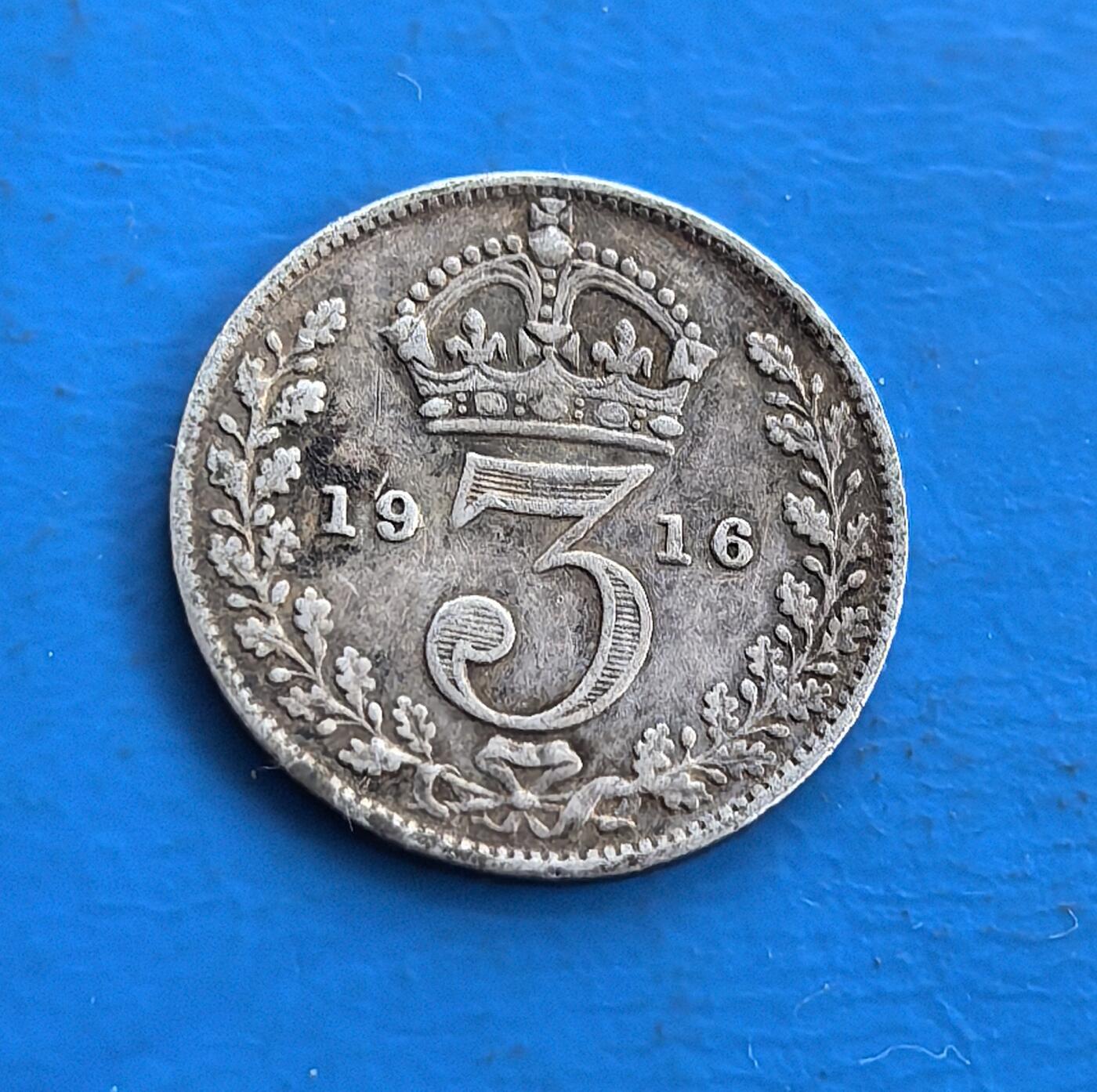 外国优质老铜币高银银币，周六九点倒数截拍，满百包邮，持续收拍 英国1916年 3 便士银币，正面乔治五世像，背面 “3” 与皇冠环绕花叶，铸于一战时期。银质包浆凝战争岁月痕，见证英帝国巅峰与动荡。属殖民时代流通币，承载君主符号与历史叙事，为研究一战货币、英王统治的稀有标本，藏帝国余晖与时代印记，小众却具厚重历史价值 。