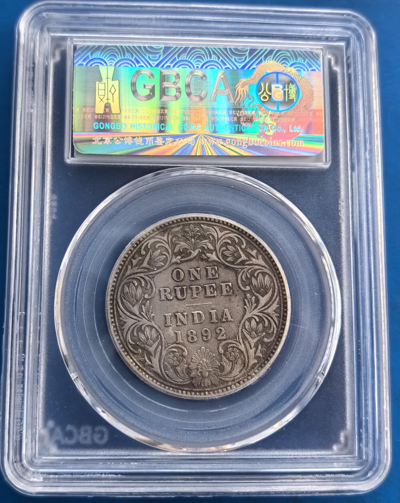 外国优质老铜币高银银币，周六九点倒数截拍，满百包邮，持续收拍 英属印度1892 年 1 卢比银币，公博评级 ，权威保真。正面维多利亚女王像刻画细腻，背面繁花簇拥的 “ONE RUPEE INDIA” 尽显殖民工艺。30.5mm 规格、11.6g 银质，百年包浆温润。作为英属印度殖民货币，见证近代历史，评级加持下品相上乘，是钱币收藏中追溯殖民文化、构建系列的优质之选，历史与收藏价值兼具 。