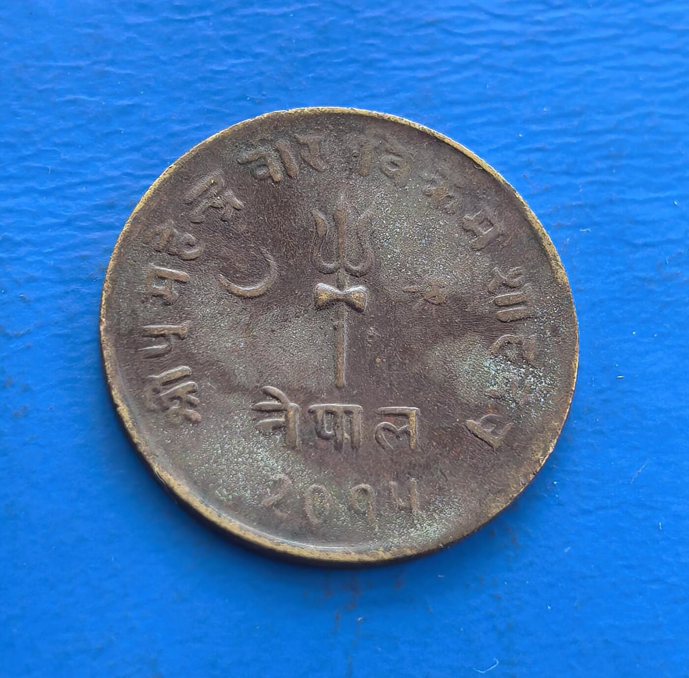 外国优质老铜币高银银币，周六九点倒数截拍，满百包邮，持续收拍 尼泊尔沙阿王朝 2094 年（约 1937 年）2 派沙铜币，正面镌湿婆三叉戟、星月（宗教符号，凝印度教文化），背面面值与尼泊尔文交织。铜质包浆载喜马拉雅古国岁月，存世因地域小众稀见。解码尼泊尔宗教图腾与王朝脉络，藏异域文化符号，是触摸喜马拉雅货币史的独特标本 。