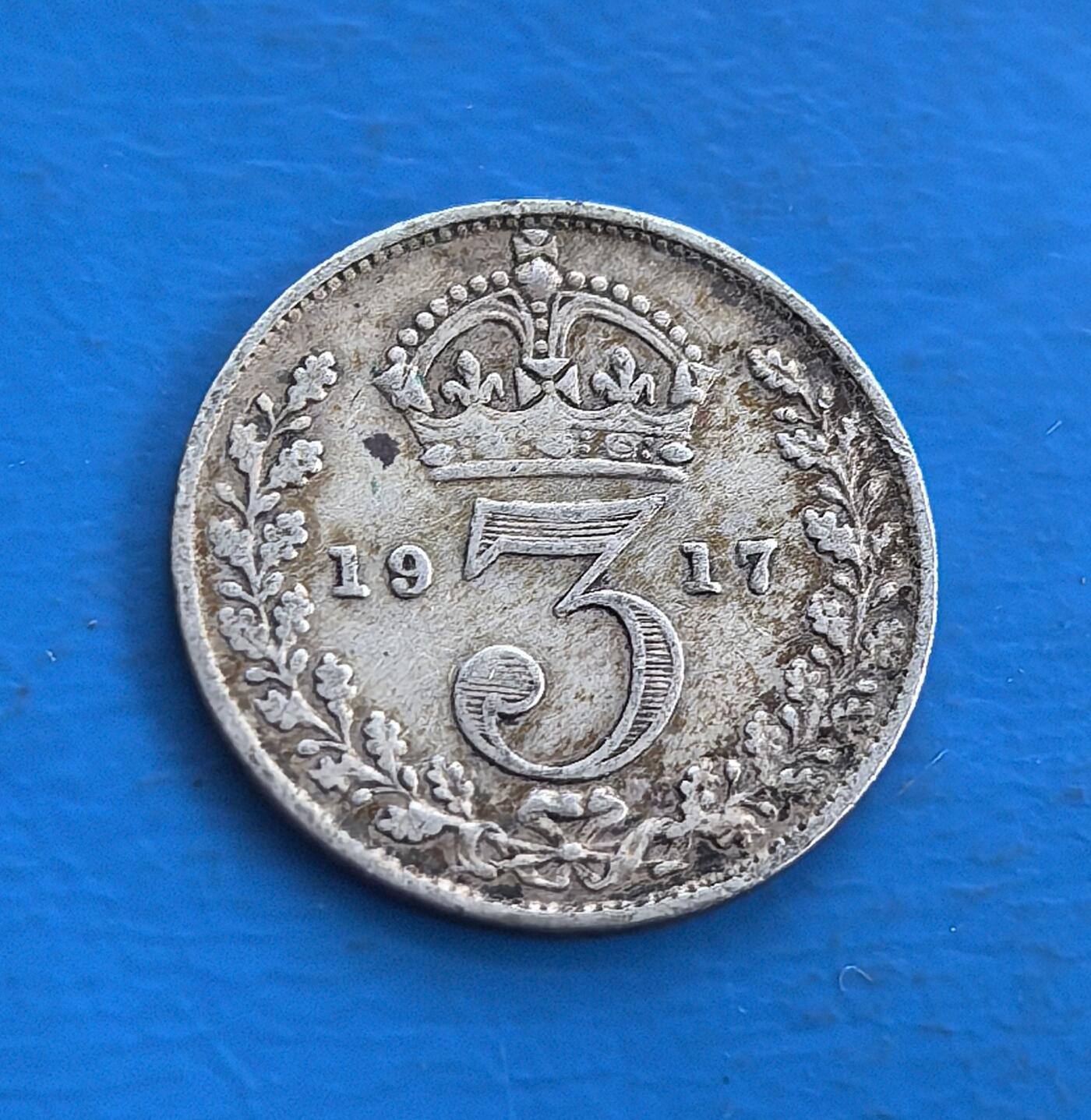 外国优质老铜币高银银币，周六九点倒数截拍，满百包邮，持续收拍 英国1917 年 3 便士银币，正面乔治五世像，背面 “3” 与皇冠环绕花叶，铸于一战时期。银质包浆凝战争岁月痕，见证英帝国巅峰与动荡。属殖民时代流通币，承载君主符号与历史叙事，为研究一战货币、英王统治的稀有标本，藏帝国余晖与时代印记，小众却具厚重历史价值 。