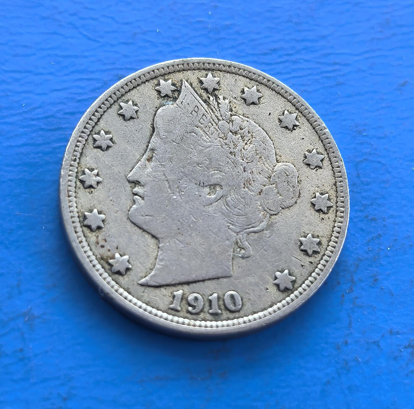外国优质老铜币高银银币，周六九点倒数截拍，满百包邮，持续收拍 美国1910 年自由5 分镍币，属经典系列（1883 - 1913）。正面自由女神冠饰、星环环绕，背面花环围 “V” ，凝萃 19 世纪末美式美学。铜镍包浆载百年痕迹，见证工业化进程，虽非稀世，却是解码美国货币史、收藏入门的亲民标的，藏历史符号与设计意趣 。