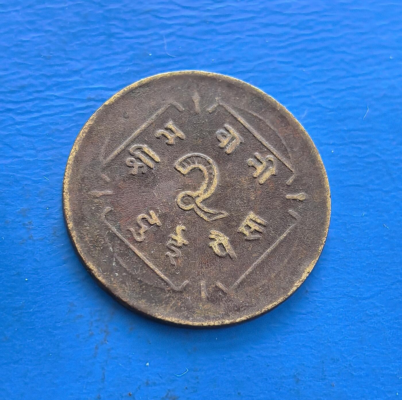 外国优质老铜币高银银币，周六九点倒数截拍，满百包邮，持续收拍 尼泊尔沙阿王朝 2094 年（约 1937 年）2 派沙铜币，正面镌湿婆三叉戟、星月（宗教符号，凝印度教文化），背面面值与尼泊尔文交织。铜质包浆载喜马拉雅古国岁月，存世因地域小众稀见。解码尼泊尔宗教图腾与王朝脉络，藏异域文化符号，是触摸喜马拉雅货币史的独特标本 。