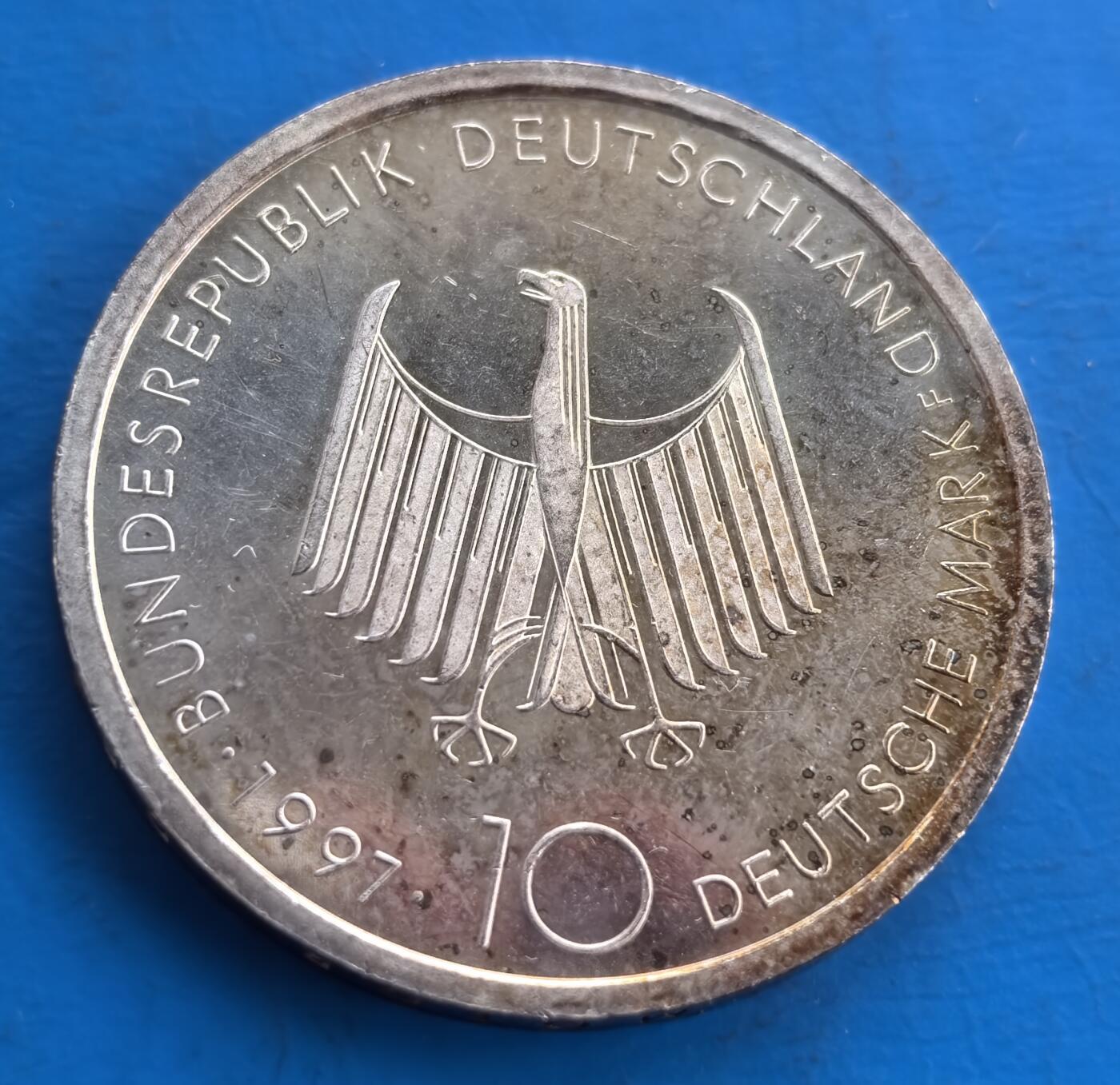 外国优质老铜币高银银币，周六九点倒数截拍，满百包邮，持续收拍 德国1997 年柴油发动机发明百周年10 马克大银币。正面饰联邦鹰徽，背面精准复刻柴油发动机结构，铭刻工业科技里程碑。德国精湛造币工艺加持，币面融合机械美学与历史厚重，是科技史与钱币收藏的跨界珍品，见证工业文明进程 。