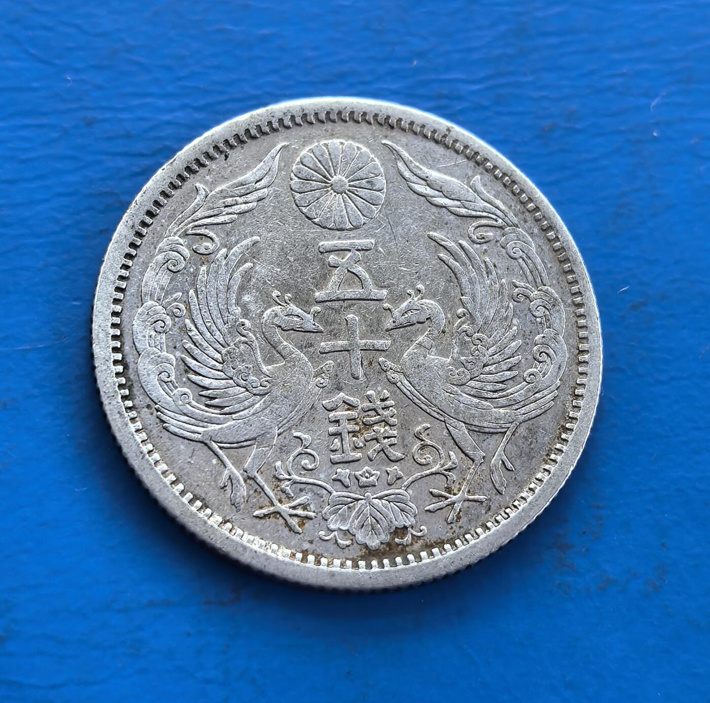 外国优质老铜币高银银币，周六九点倒数截拍，满百包邮，持续收拍 日本大正十二年（1923 年）五十钱银币，正面双凤衔枝环绕日章，背面菊花纹章配年号，银质温润。见证大正民主期货币美学，凤纹寓祥瑞，工艺融传统与近代铸币技。存世因岁月流通渐稀，承载东瀛货币文化脉络，是解码日本大正时代、收藏凤纹银币的独特标的 。