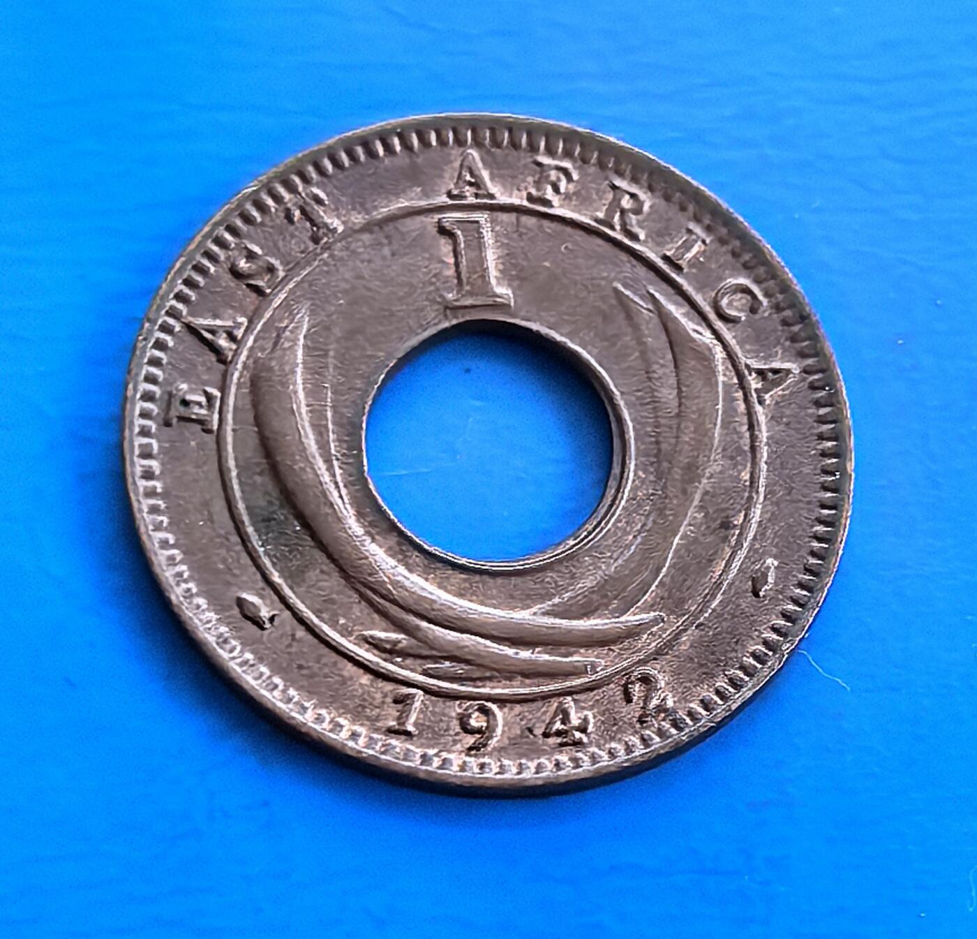 外国优质老铜币高银银币，周六九点倒数截拍，满百包邮，持续收拍 英属东非1942 年 1 分I版，中孔设计独特。正面刻乔治六世王冠及王室铭文，背面 “EAST AFRICA” 彰显殖民属性。诞生于二战胶着期，见证英属东非历史与战争脉络，包浆凝岁月痕迹。作为非洲殖民币小众品类，独特形制 + 战争背景，解码英帝国殖民遗产，收藏兼具历史厚重与设计意趣 。