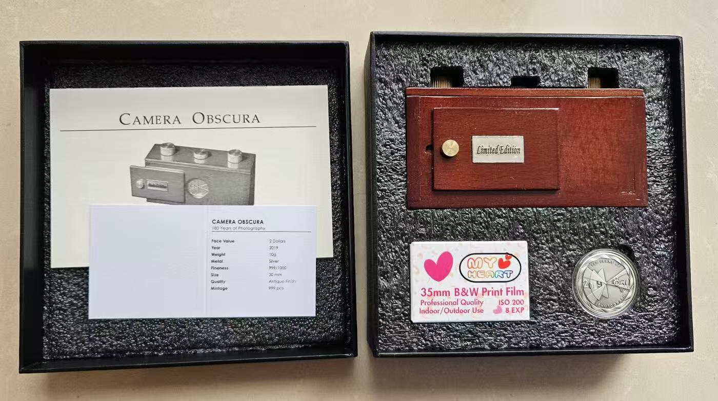 ❤️【币观天下】❤️ 第337期钱币拍卖- 2026.1.2周五晚上6点半场-长期征集拍品 帕劳2019年照相术180年纪念银币面值2元，925银10克，直径30毫米，中间微孔，仿古，发行999枚 带证书，包装为一个可实用的古典暗盒式照相机，配胶卷和使用说明。