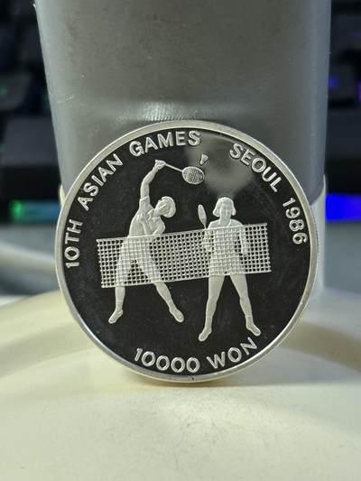第186期拍卖 - 韩国1986年第十届亚洲运动会羽毛球纪念银币，900银，23克银价373，有瑕疵，没有塑料盒