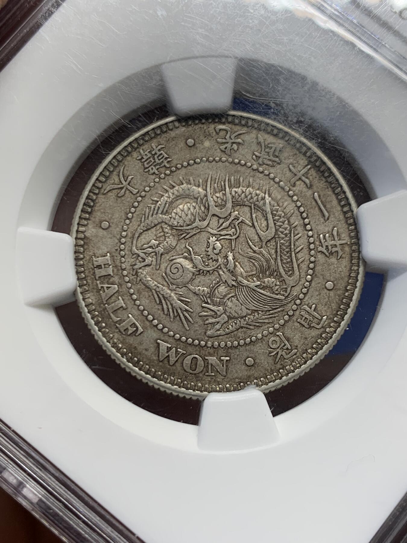 《竞宝斋》第454场 周日，周一 2场连拍 （全场包邮，欢迎送拍） NGC AU58  朝鲜1907年光武十一年半圆 小版稀少年份 百年原味通体自然老彩，正面蟠龙戏珠图，龙身盘踞如环，背面上方为“李花章”（五瓣木槿花），下方交叉的桔梗花（左）与李花（右）