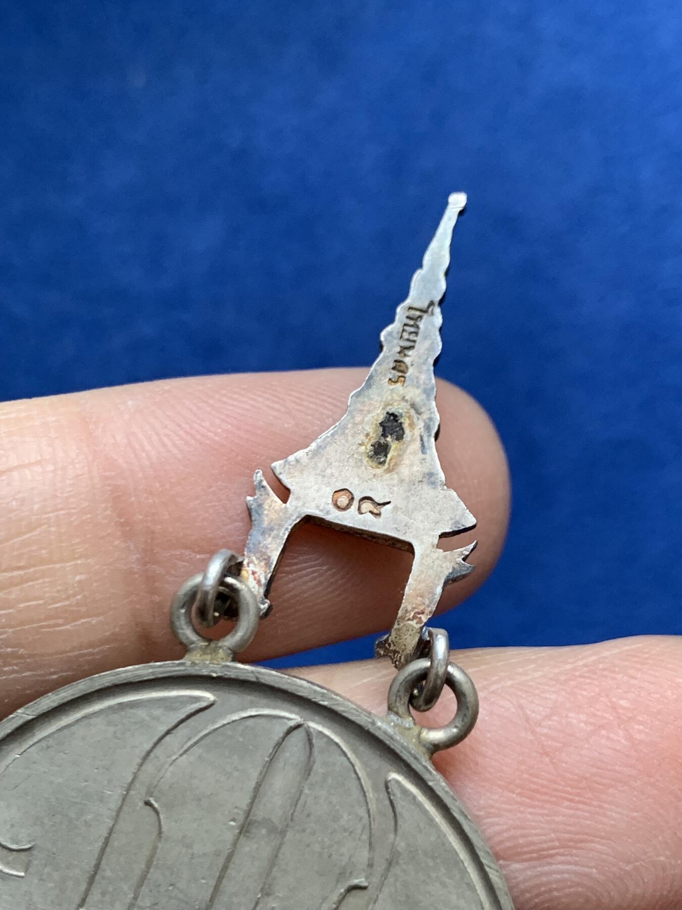 《竞宝斋》第454场 周日，周一 2场连拍 （全场包邮，欢迎送拍） 原盒 泰国银质白象宝塔勋章，历史可以追溯到1861年由当时的君主拉玛四世创立。约上世纪中期发行，佛塔背面有泰文戳记，裸章重约：21.5克。原盒原绶带。这个勋章专门为表彰那些在艺术、科学、商业、外交等领域有杰出贡献的知名人士，状态如图，近未使用品，疑似背面挂环脱落，介意勿拍！