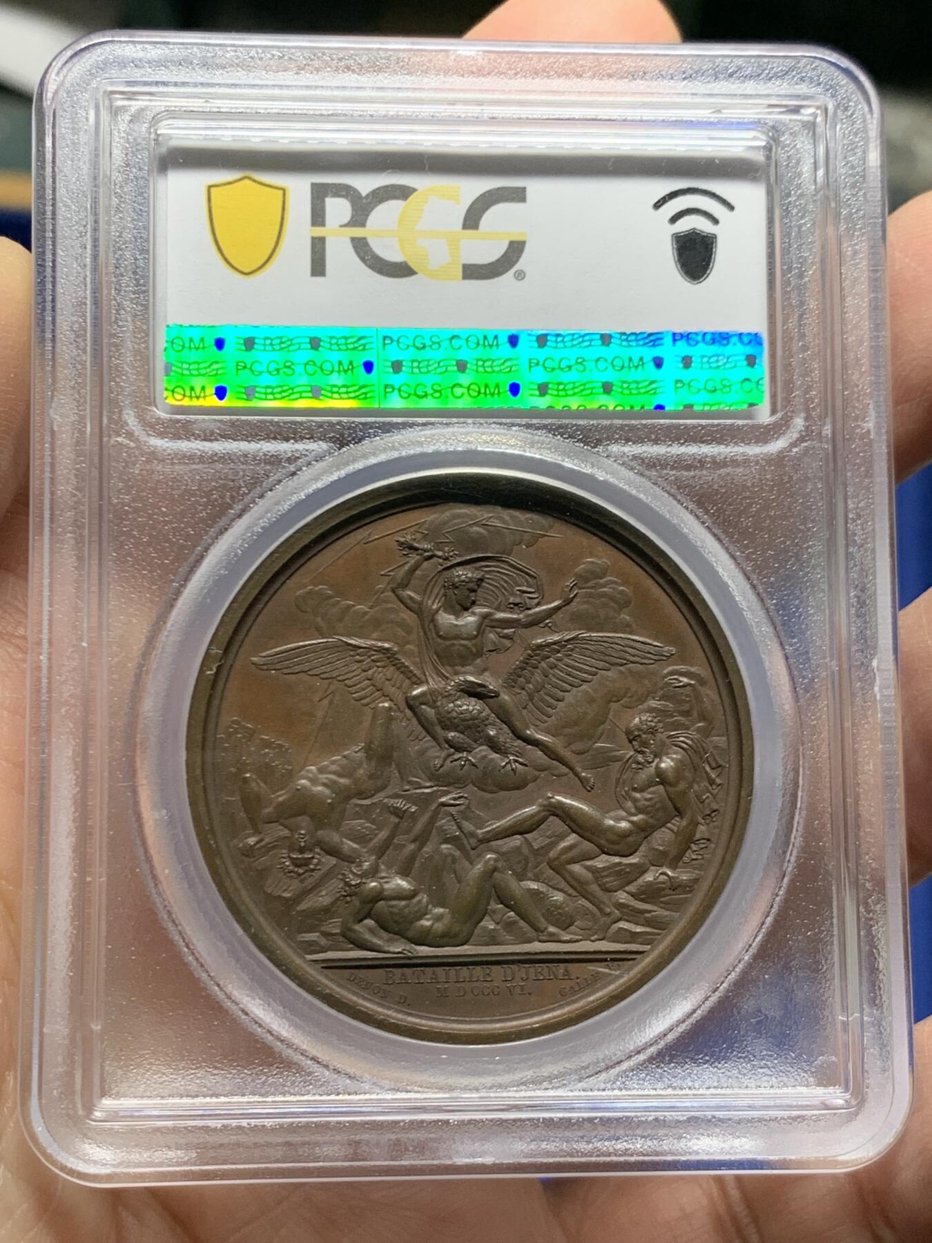 《竞宝斋》第455场 周日，周一 2场连拍 （全场包邮，欢迎送拍） PCGS SP64 法国1806年拿破仑一世耶拿之战原铸铜章 巴黎造币厂 巧克力包浆 拿破仑化身朱庇特（罗马神话中众神之王）身披斗篷骑着帝国之鹰腾云凌空 手持闪电权杖 击倒斩杀地上三名巨人 场面英武壮阔 设计大胆天马行空 肌肉线条精细优美 该战役是拿破仑大破普军经典战役 也是拿章中经典中的经典