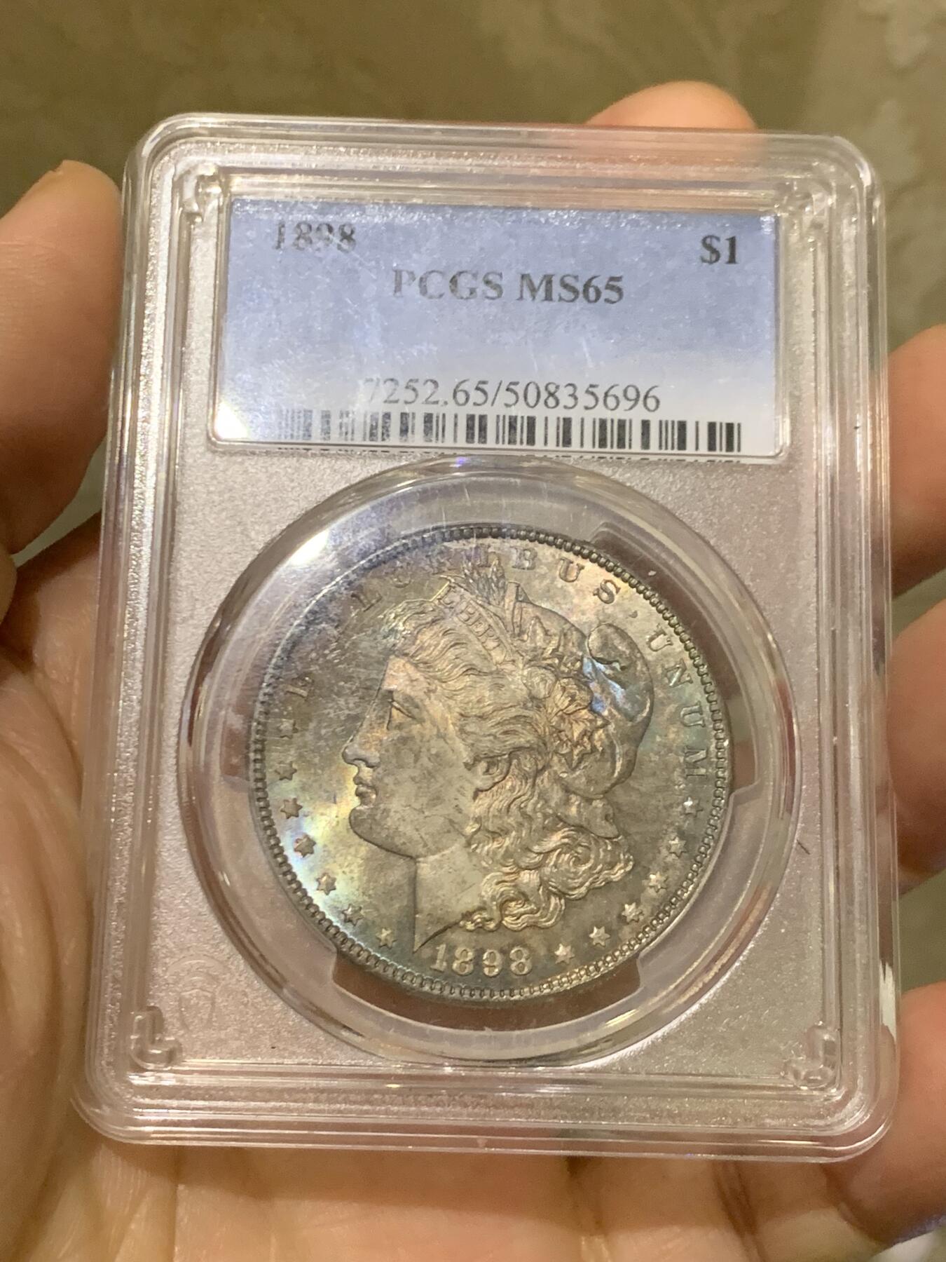 《竞宝斋》第455场 周日，周一 2场连拍 （全场包邮，欢迎送拍） PCGS MS65 美国1898年摩根一美元银币，1898年年份较少，本枚为标准卷首彩，美轮美奂，绚丽五彩，值得重新送评