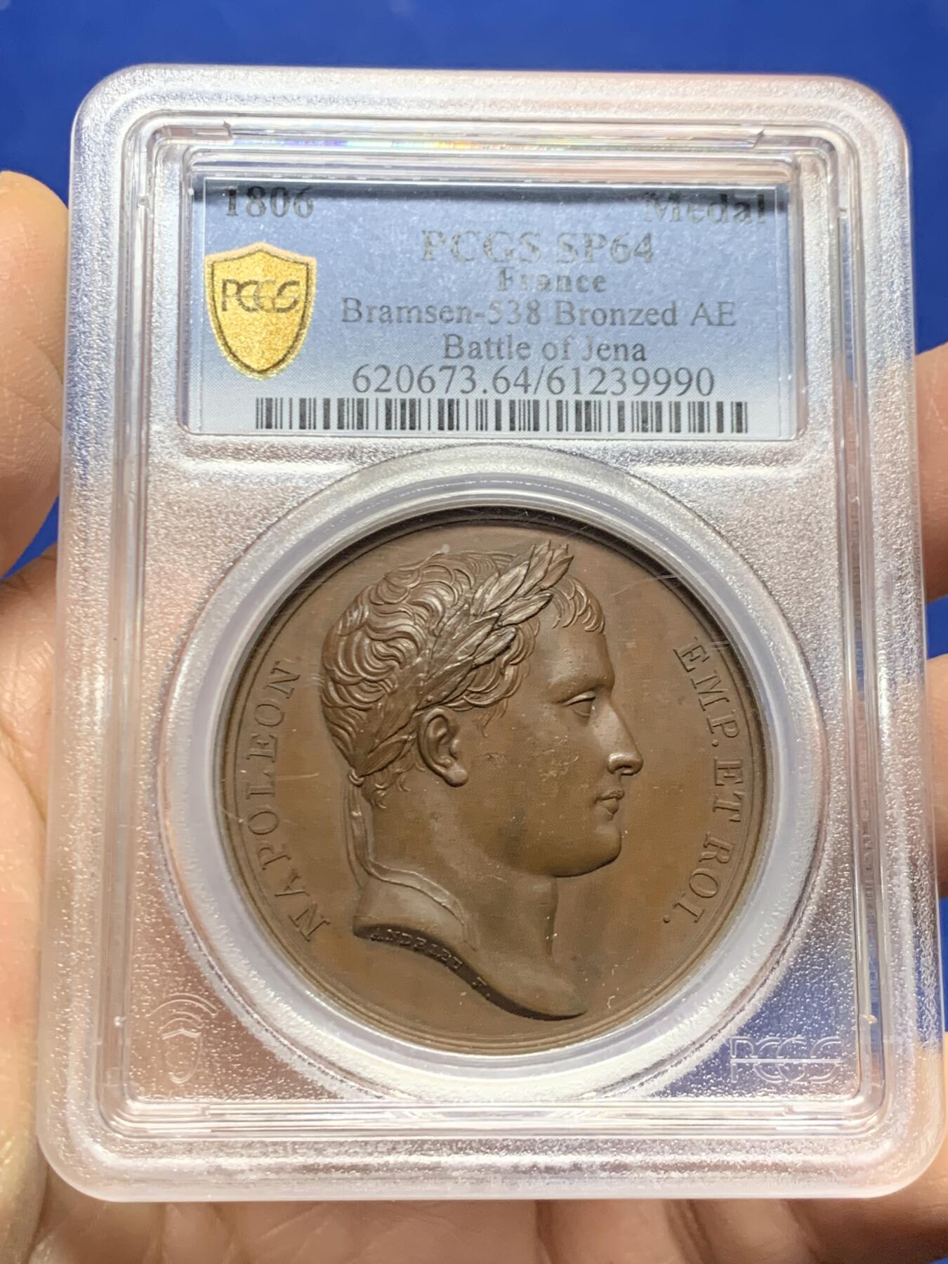《竞宝斋》第455场 周日，周一 2场连拍 （全场包邮，欢迎送拍） PCGS SP64 法国1806年拿破仑一世耶拿之战原铸铜章 巴黎造币厂 巧克力包浆 拿破仑化身朱庇特（罗马神话中众神之王）身披斗篷骑着帝国之鹰腾云凌空 手持闪电权杖 击倒斩杀地上三名巨人 场面英武壮阔 设计大胆天马行空 肌肉线条精细优美 该战役是拿破仑大破普军经典战役 也是拿章中经典中的经典