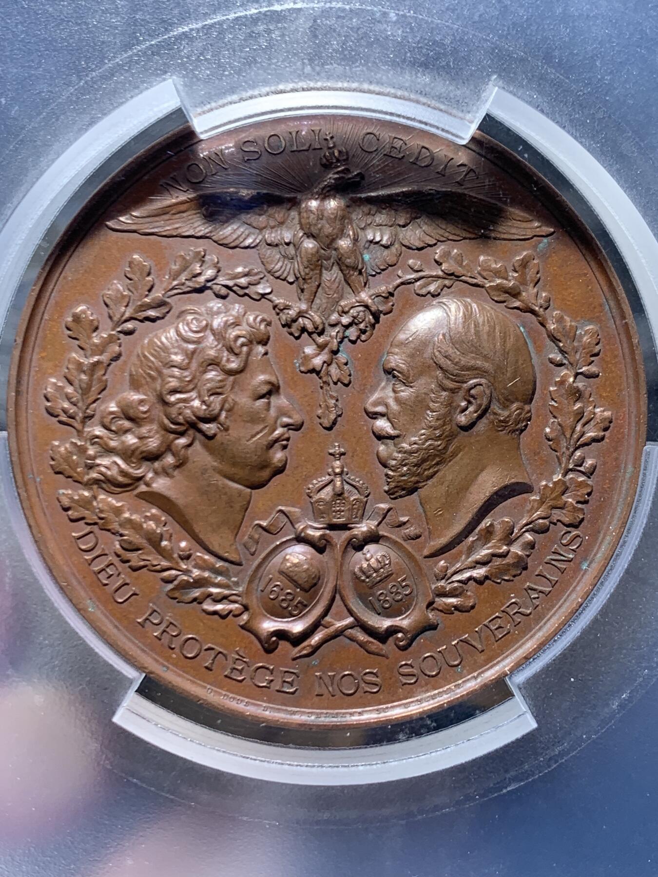 《竞宝斋》第455场 周日，周一 2场连拍 （全场包邮，欢迎送拍） PCGS SP62 德国普鲁士1885年纪念柏林法国教区成立200周年大铜章，少见品。正面图案：花枝环绕下，弗里德里希大帝和威廉一世的侧像，在两顶加冕皇冠的衬托下，冠冕头鹰两翼张开，气势非凡。反面图案：波卢西亚女神手握剑和盾牌，守护着孩子们。精美的高浮雕铜章，极具收藏价值。加大加厚盒