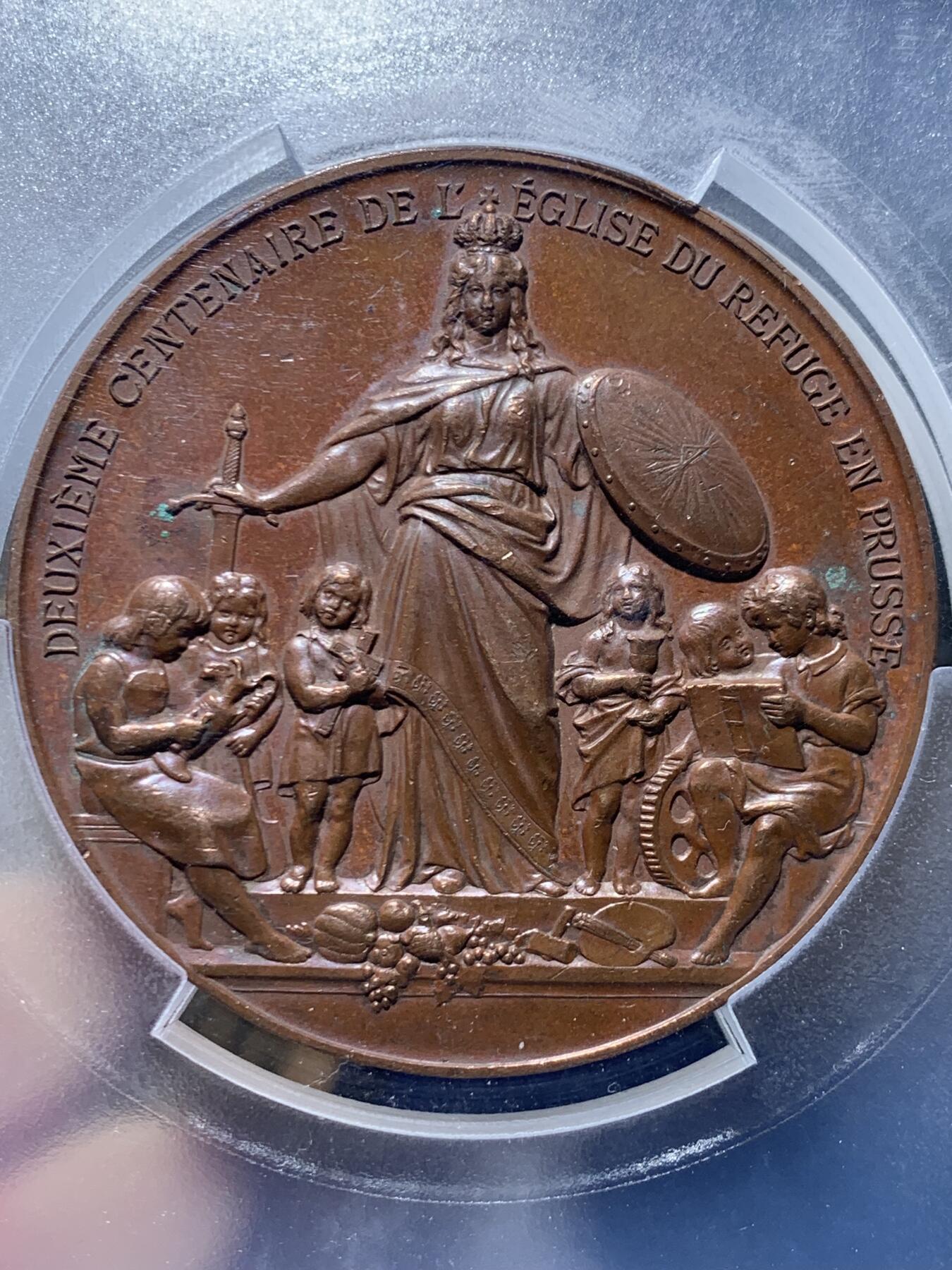 《竞宝斋》第455场 周日，周一 2场连拍 （全场包邮，欢迎送拍） PCGS SP62 德国普鲁士1885年纪念柏林法国教区成立200周年大铜章，少见品。正面图案：花枝环绕下，弗里德里希大帝和威廉一世的侧像，在两顶加冕皇冠的衬托下，冠冕头鹰两翼张开，气势非凡。反面图案：波卢西亚女神手握剑和盾牌，守护着孩子们。精美的高浮雕铜章，极具收藏价值。加大加厚盒