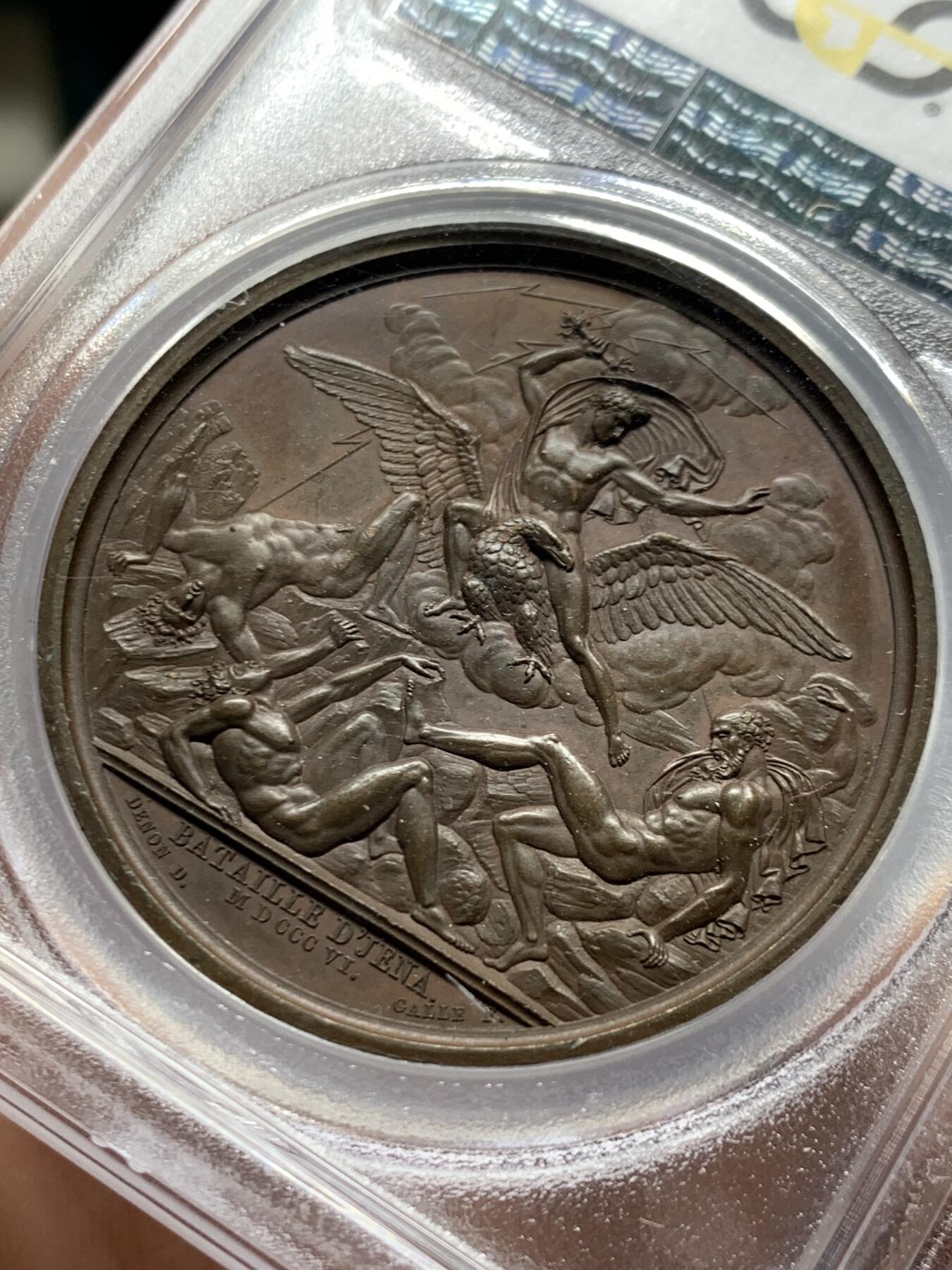 《竞宝斋》第455场 周日，周一 2场连拍 （全场包邮，欢迎送拍） PCGS SP64 法国1806年拿破仑一世耶拿之战原铸铜章 巴黎造币厂 巧克力包浆 拿破仑化身朱庇特（罗马神话中众神之王）身披斗篷骑着帝国之鹰腾云凌空 手持闪电权杖 击倒斩杀地上三名巨人 场面英武壮阔 设计大胆天马行空 肌肉线条精细优美 该战役是拿破仑大破普军经典战役 也是拿章中经典中的经典
