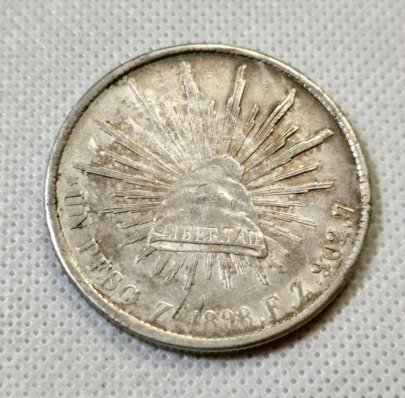 甄臻铺-世界币章拍卖（第46期）送拍享返佣金等优惠多多（1月10日精品场，敬请期待） 墨西哥鹰洋，1898ZS FZ原铸版，此版常见弱打，这枚是少见的全羽毛UNC品相，鹰头和蛇头的表情清晰，对光可看到带有红绿蓝彩色渐变，细节见图