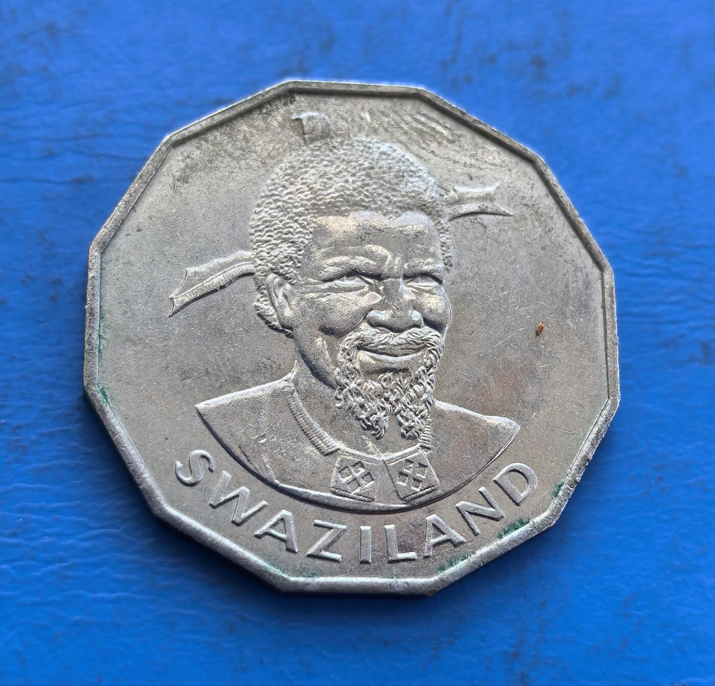 外国优质银币非洲美洲币，周六九点倒数截拍，满百包邮，持续收拍 斯威士兰1975年50 分八角形硬币，正面是国王索布扎二世像（带传统装饰），背面展国徽（狮、象护盾 +“我们是勇士” 标语），风格体现其王室文化与国家标识，是南部非洲特色货币收藏之选。