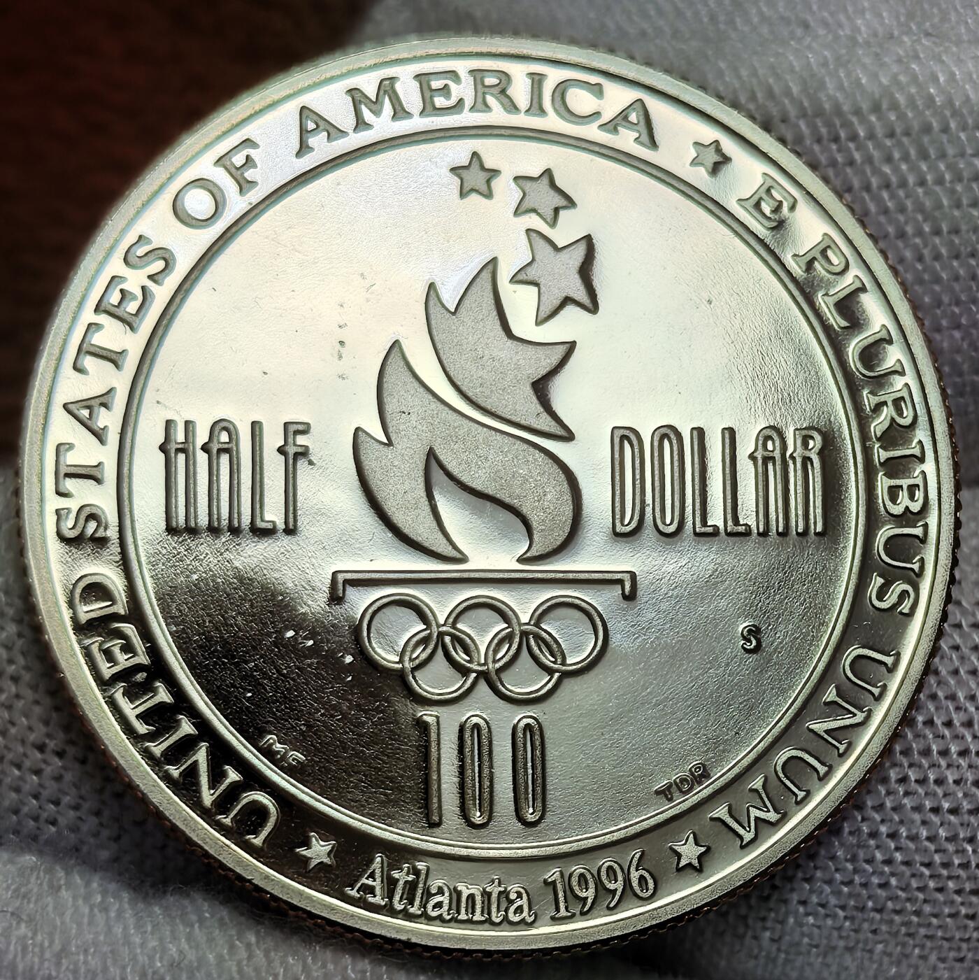 外国优质银币非洲美洲币，周六九点倒数截拍，满百包邮，持续收拍 稀少精制币美国1996 年亚特兰大奥运半元，正面绘女足运动员竞技场景，背面展奥运火炬与五环，题材关联百年奥运，精制币细节生动，具体育纪念与收藏价值。