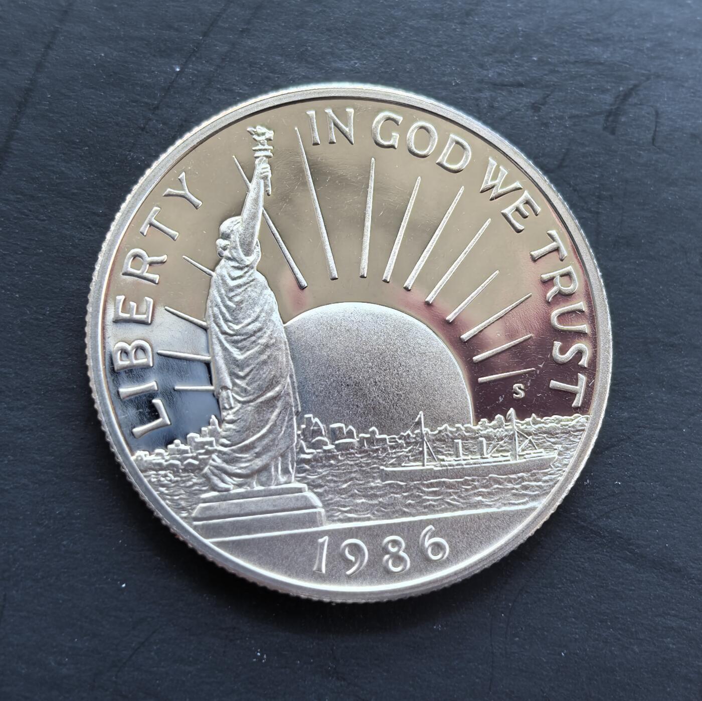 外国优质银币非洲美洲币，周六九点倒数截拍，满百包邮，持续收拍 稀少精制币美国1986 年移民主题精制半元，正面绘自由女神像，背面展移民登岸场景，题材呼应 “移民之国” 定位，精制币细节饱满，具人文纪念与收藏价值。