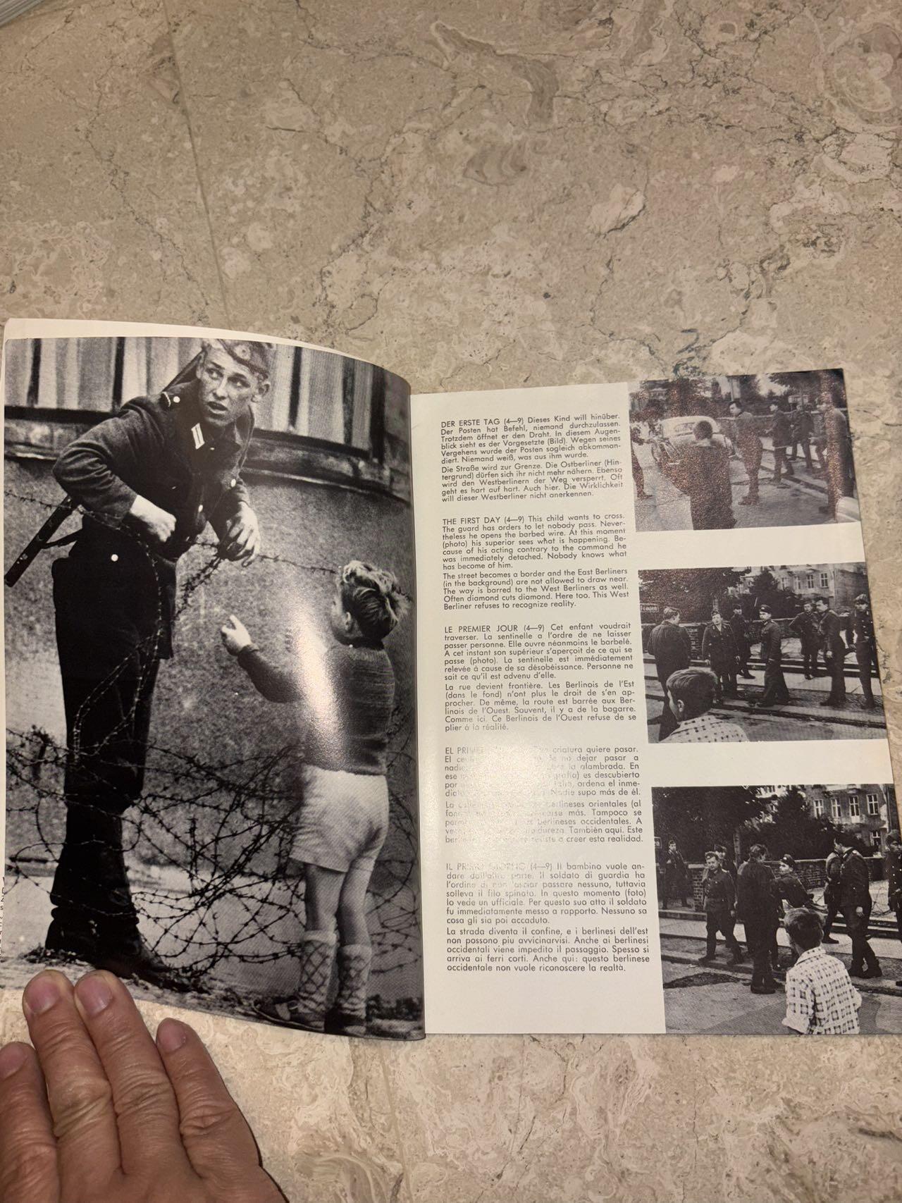 盛世勋华——号角文化勋章邮票专场拍卖第298期 德国柏林墙文献《发生在墙边的事》，附带荷兰语报纸对柏林墙相关历史的专题报道，记录了1961年8月13日柏林墙修建至1989年倒塌期间，西柏林周边封锁带的发展与关键事件。全书127页，采用黑白纪实摄影，左侧是守卫柏林墙的士兵形象，右侧是柏林墙相关事件的纪实小图（如越墙尝试、热气球逃亡、地标建筑等），直观展现冷战时期柏林的分裂状态。