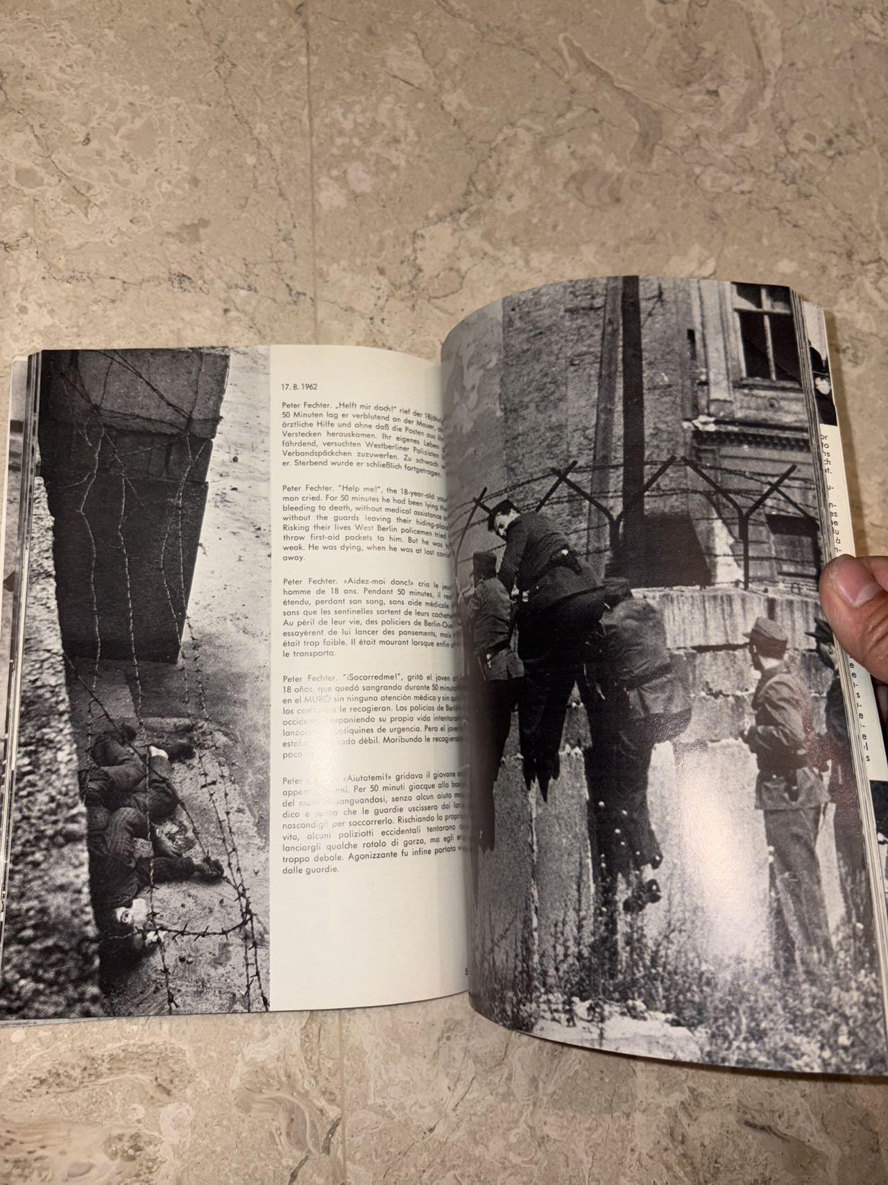 盛世勋华——号角文化勋章邮票专场拍卖第298期 德国柏林墙文献《发生在墙边的事》，附带荷兰语报纸对柏林墙相关历史的专题报道，记录了1961年8月13日柏林墙修建至1989年倒塌期间，西柏林周边封锁带的发展与关键事件。全书127页，采用黑白纪实摄影，左侧是守卫柏林墙的士兵形象，右侧是柏林墙相关事件的纪实小图（如越墙尝试、热气球逃亡、地标建筑等），直观展现冷战时期柏林的分裂状态。