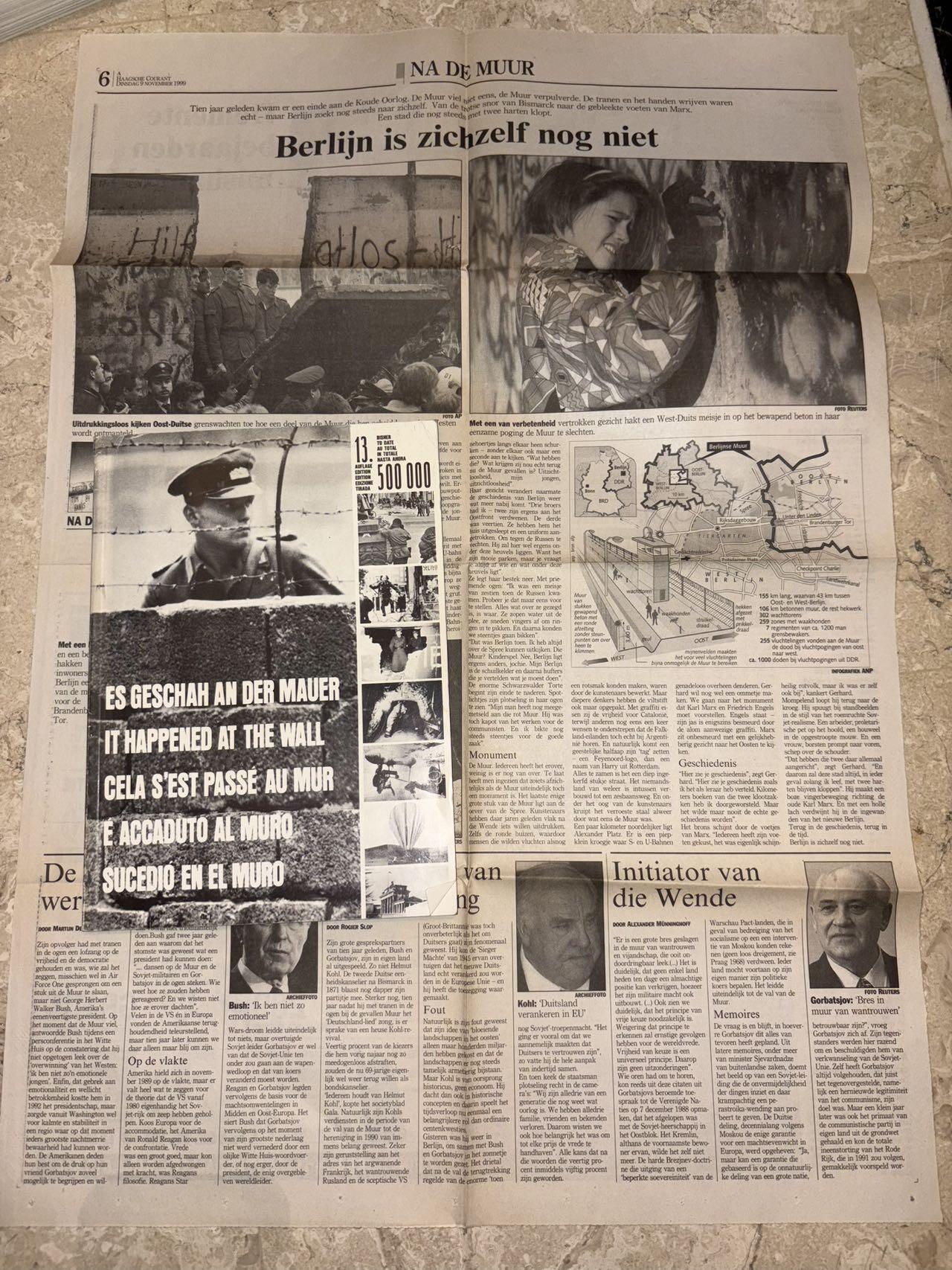 盛世勋华——号角文化勋章邮票专场拍卖第298期 德国柏林墙文献《发生在墙边的事》，附带荷兰语报纸对柏林墙相关历史的专题报道，记录了1961年8月13日柏林墙修建至1989年倒塌期间，西柏林周边封锁带的发展与关键事件。全书127页，采用黑白纪实摄影，左侧是守卫柏林墙的士兵形象，右侧是柏林墙相关事件的纪实小图（如越墙尝试、热气球逃亡、地标建筑等），直观展现冷战时期柏林的分裂状态。