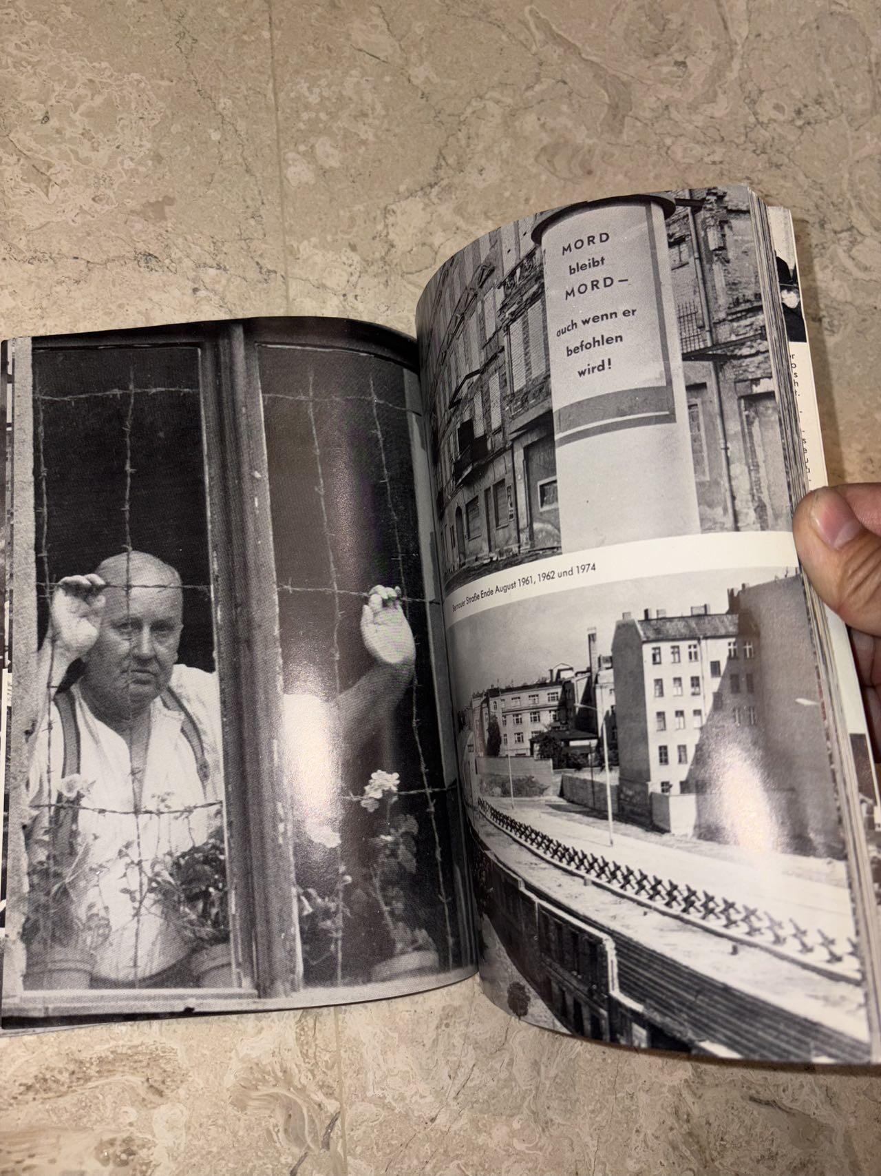 盛世勋华——号角文化勋章邮票专场拍卖第298期 德国柏林墙文献《发生在墙边的事》，附带荷兰语报纸对柏林墙相关历史的专题报道，记录了1961年8月13日柏林墙修建至1989年倒塌期间，西柏林周边封锁带的发展与关键事件。全书127页，采用黑白纪实摄影，左侧是守卫柏林墙的士兵形象，右侧是柏林墙相关事件的纪实小图（如越墙尝试、热气球逃亡、地标建筑等），直观展现冷战时期柏林的分裂状态。