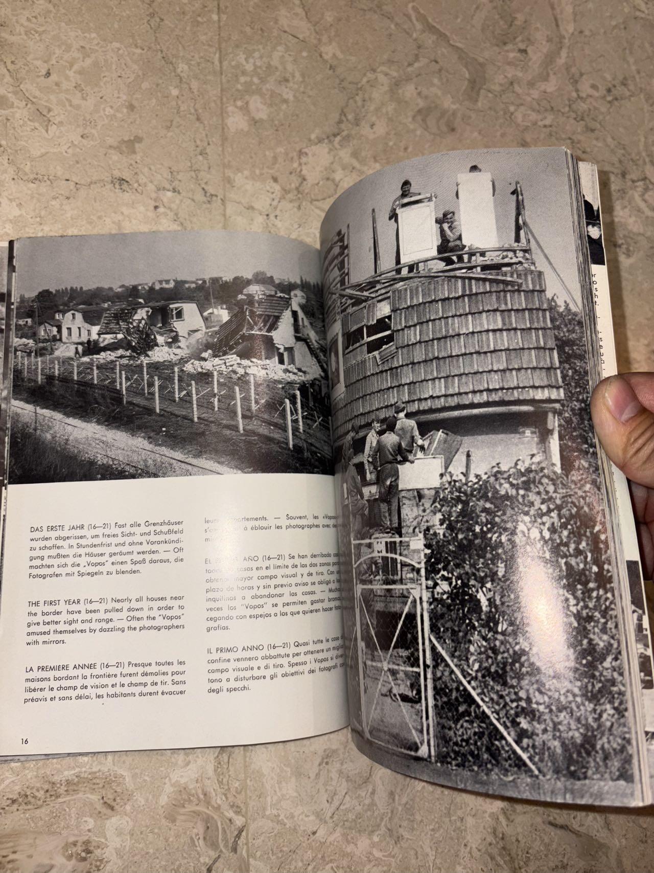 盛世勋华——号角文化勋章邮票专场拍卖第298期 德国柏林墙文献《发生在墙边的事》，附带荷兰语报纸对柏林墙相关历史的专题报道，记录了1961年8月13日柏林墙修建至1989年倒塌期间，西柏林周边封锁带的发展与关键事件。全书127页，采用黑白纪实摄影，左侧是守卫柏林墙的士兵形象，右侧是柏林墙相关事件的纪实小图（如越墙尝试、热气球逃亡、地标建筑等），直观展现冷战时期柏林的分裂状态。