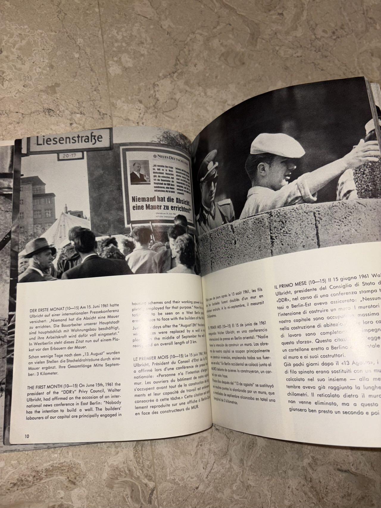 盛世勋华——号角文化勋章邮票专场拍卖第298期 德国柏林墙文献《发生在墙边的事》，附带荷兰语报纸对柏林墙相关历史的专题报道，记录了1961年8月13日柏林墙修建至1989年倒塌期间，西柏林周边封锁带的发展与关键事件。全书127页，采用黑白纪实摄影，左侧是守卫柏林墙的士兵形象，右侧是柏林墙相关事件的纪实小图（如越墙尝试、热气球逃亡、地标建筑等），直观展现冷战时期柏林的分裂状态。