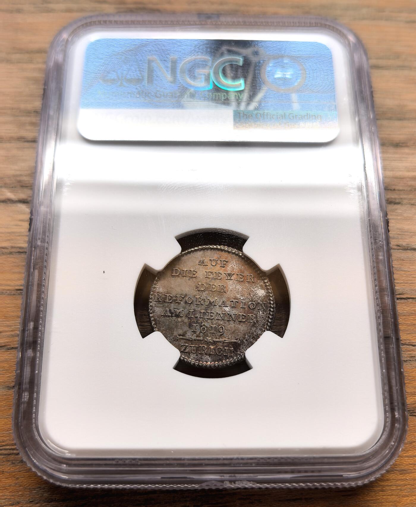 凡希社世界钱币微拍第三百十八期 1819瑞士宗教改革300周年杜卡特银质试铸币NGC-MS63，传世五彩，稀有。正面为瑞士宗教改革领袖乌尔里希·慈运理的侧面半身像，慈运理是苏黎世宗教改革的核心人物，与马丁·路德、加尔文并称欧洲宗教改革三大领袖；背面文字：“1819年1月1日苏黎世宗教改革庆典”。