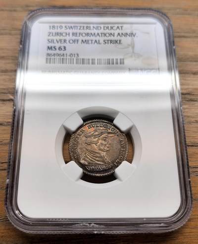 凡希社世界钱币微拍第三百十八期 - 1819瑞士宗教改革300周年杜卡特银质试铸币NGC-MS63，传世五彩，稀有。正面为瑞士宗教改革领袖乌尔里希·慈运理的侧面半身像，慈运理是苏黎世宗教改革的核心人物，与马丁·路德、加尔文并称欧洲宗教改革三大领袖；背面文字：“1819年1月1日苏黎世宗教改革庆典”。