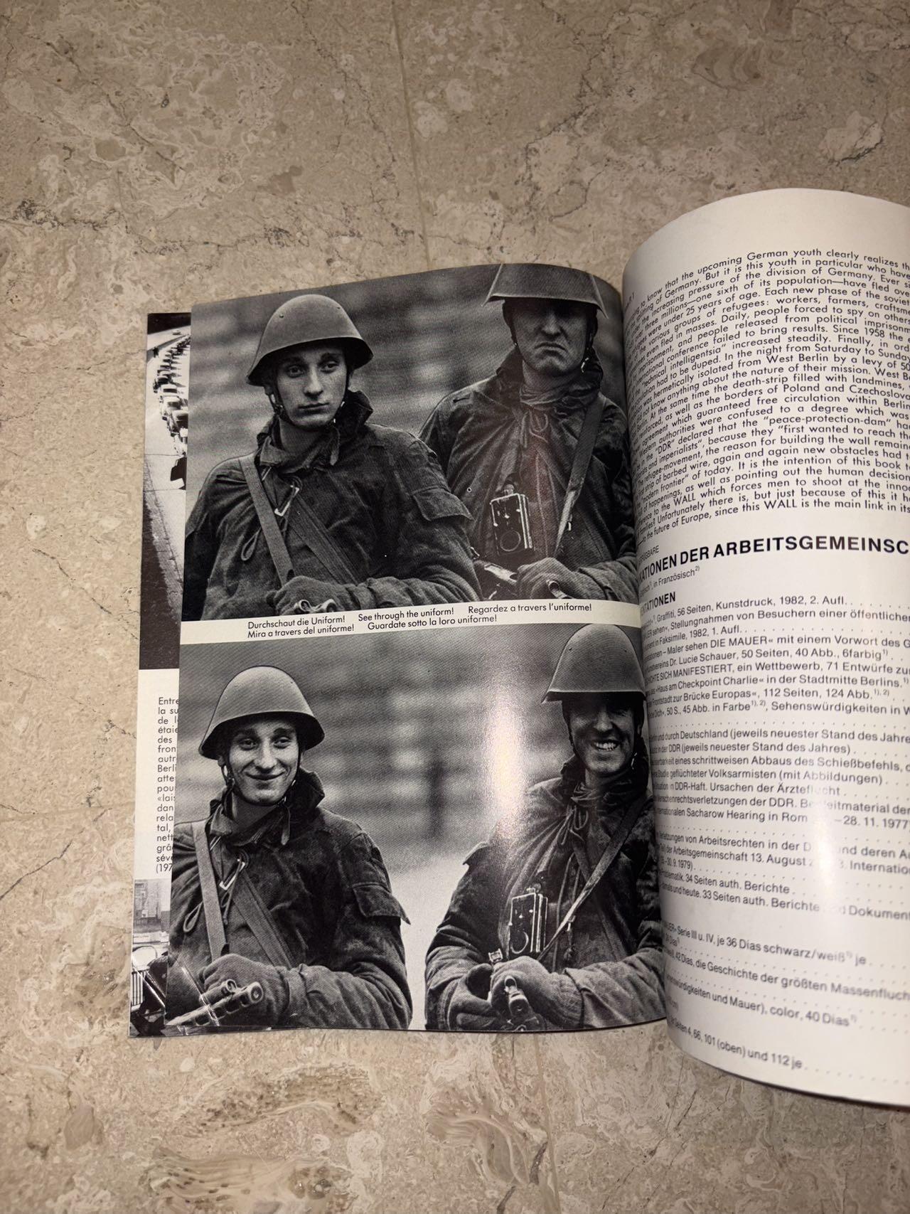 盛世勋华——号角文化勋章邮票专场拍卖第298期 德国柏林墙文献《发生在墙边的事》，附带荷兰语报纸对柏林墙相关历史的专题报道，记录了1961年8月13日柏林墙修建至1989年倒塌期间，西柏林周边封锁带的发展与关键事件。全书127页，采用黑白纪实摄影，左侧是守卫柏林墙的士兵形象，右侧是柏林墙相关事件的纪实小图（如越墙尝试、热气球逃亡、地标建筑等），直观展现冷战时期柏林的分裂状态。