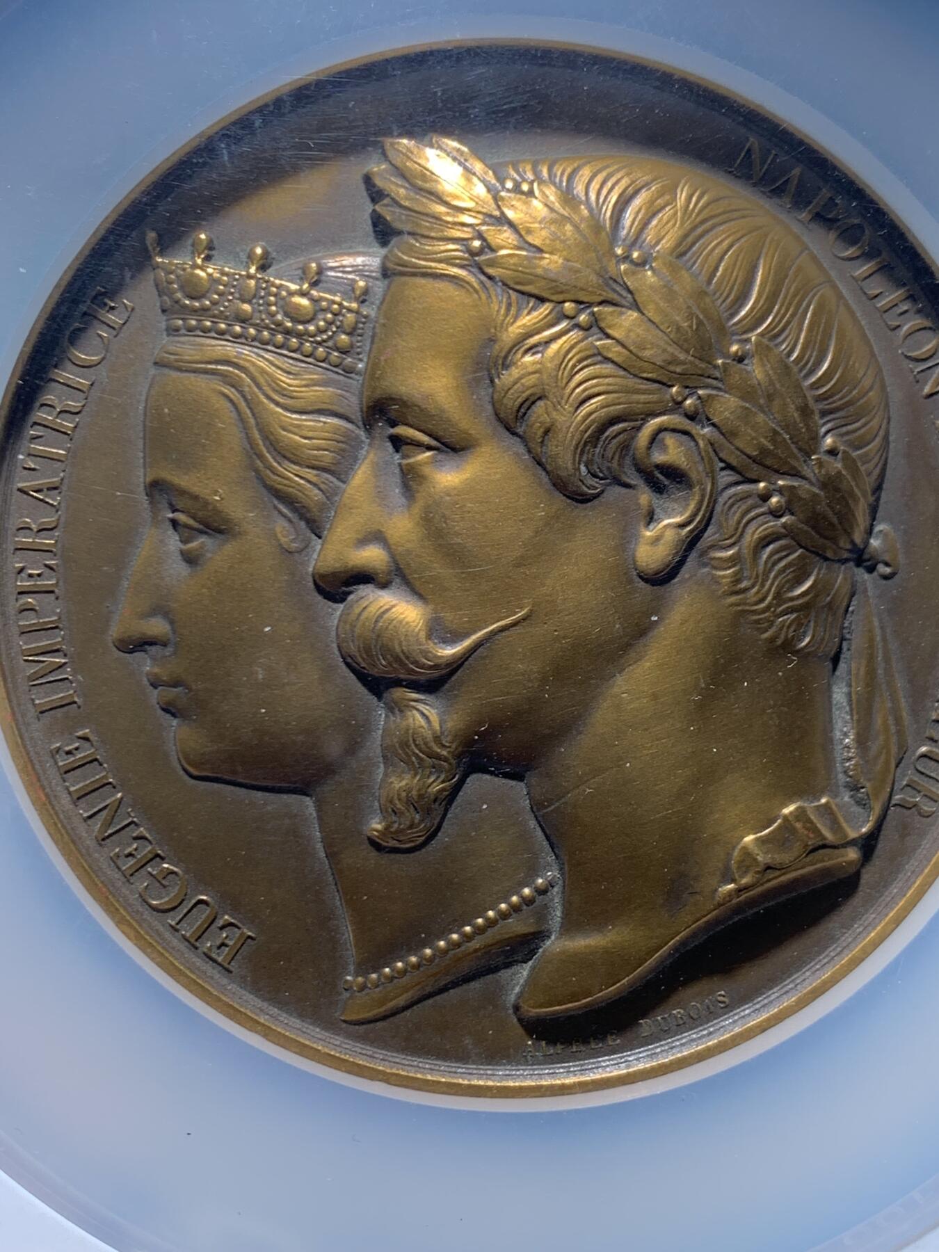 《竞宝斋》第456场 周日，周一，周二   3场连拍 （全场包邮）欢迎送拍 NGC MS61BN 法国拿破仑三世与欧仁妮皇后在1980年为王子洗礼高浮雕大铜章 ，正面呈现拿破仑三世与欧仁妮皇后的左侧面肖像，人物细节刻画精细，经典纪念章藏品 ，该章直径70mm，加大加厚盒封装。