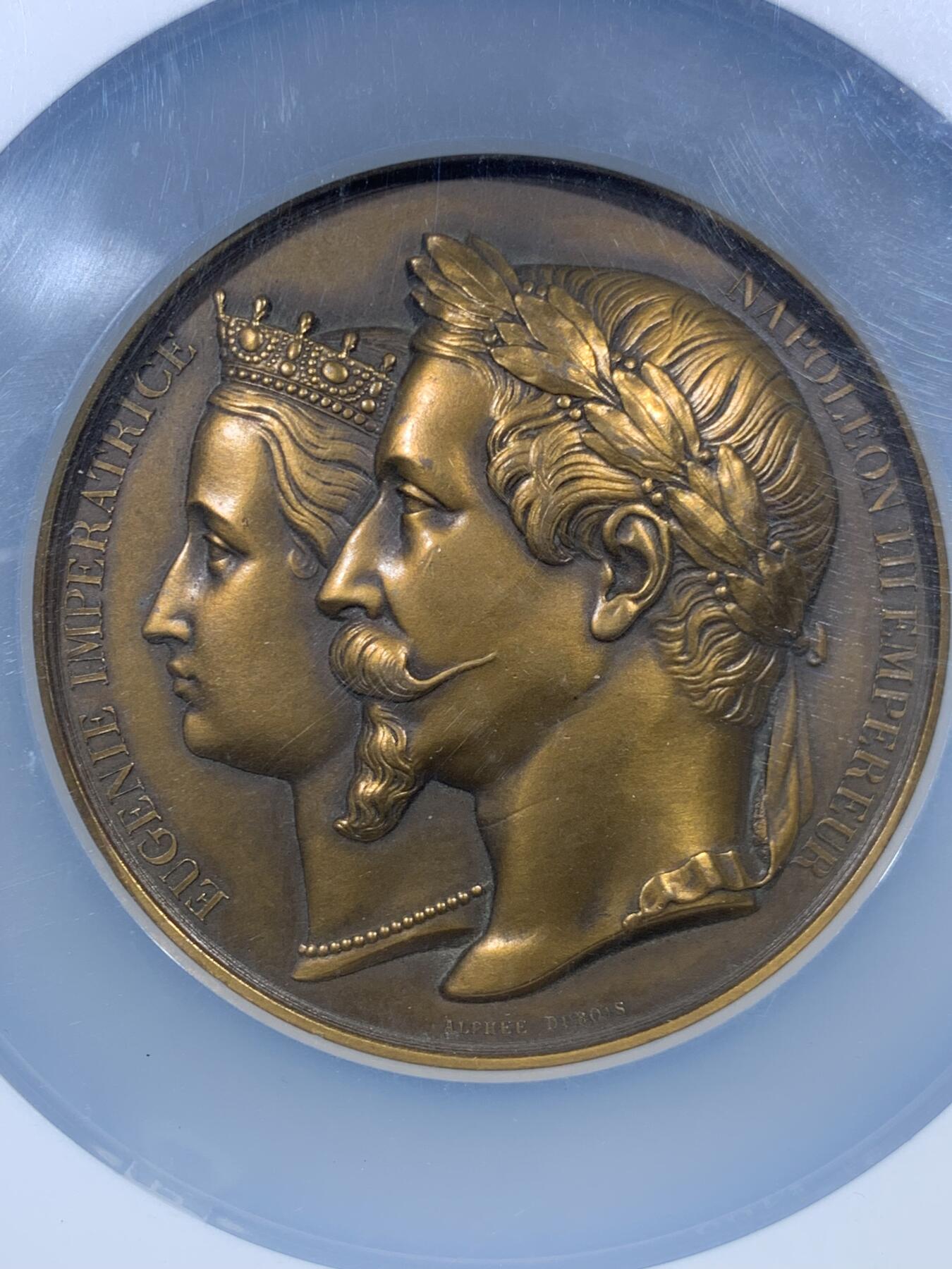 《竞宝斋》第456场 周日，周一，周二   3场连拍 （全场包邮）欢迎送拍 NGC MS61BN 法国拿破仑三世与欧仁妮皇后在1980年为王子洗礼高浮雕大铜章 ，正面呈现拿破仑三世与欧仁妮皇后的左侧面肖像，人物细节刻画精细，经典纪念章藏品 ，该章直径70mm，加大加厚盒封装。